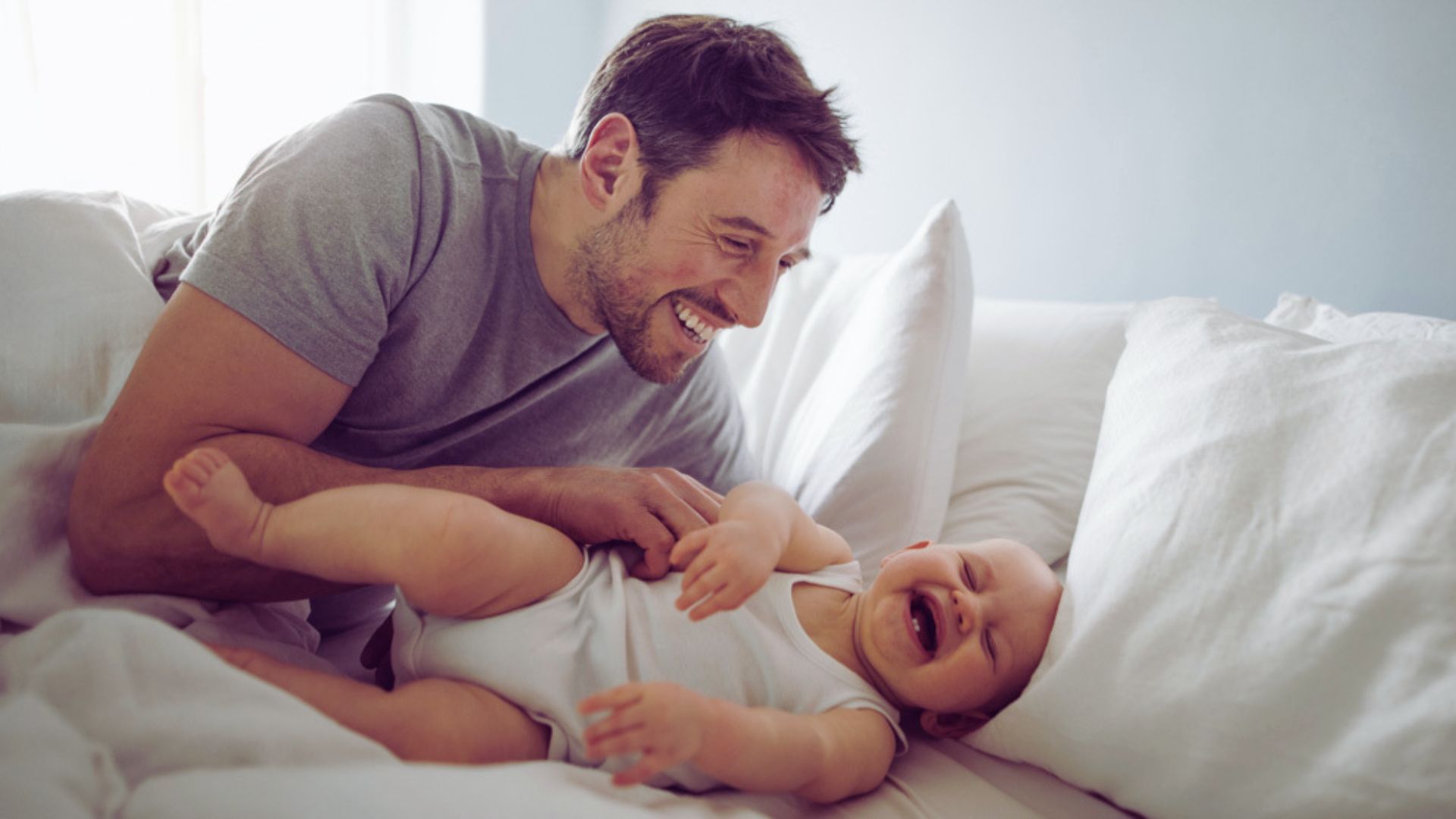 A man and an infant are resting in bed, showcasing a serene and intimate bonding moment.