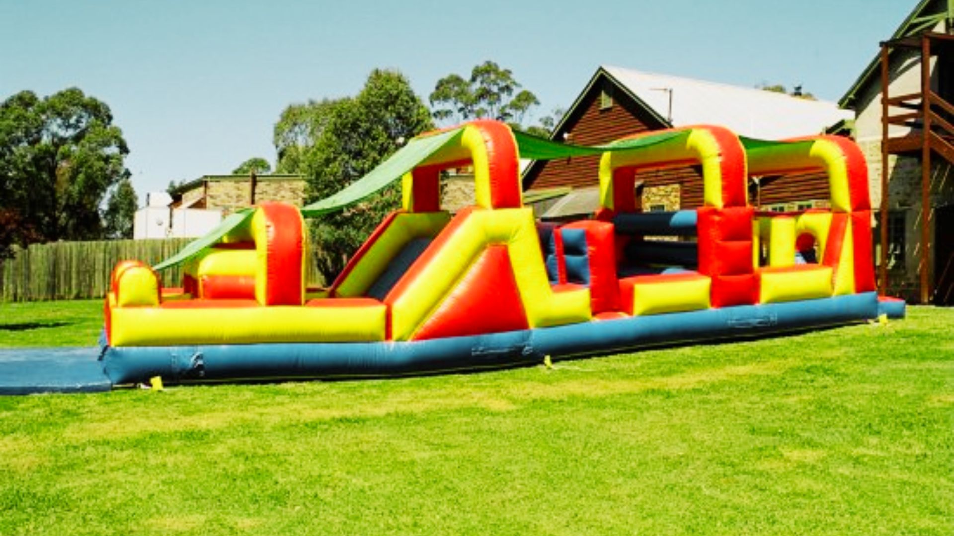A large inflatable obstacle course set up in a backyard, featuring colorful slides and climbing sections for outdoor fun.