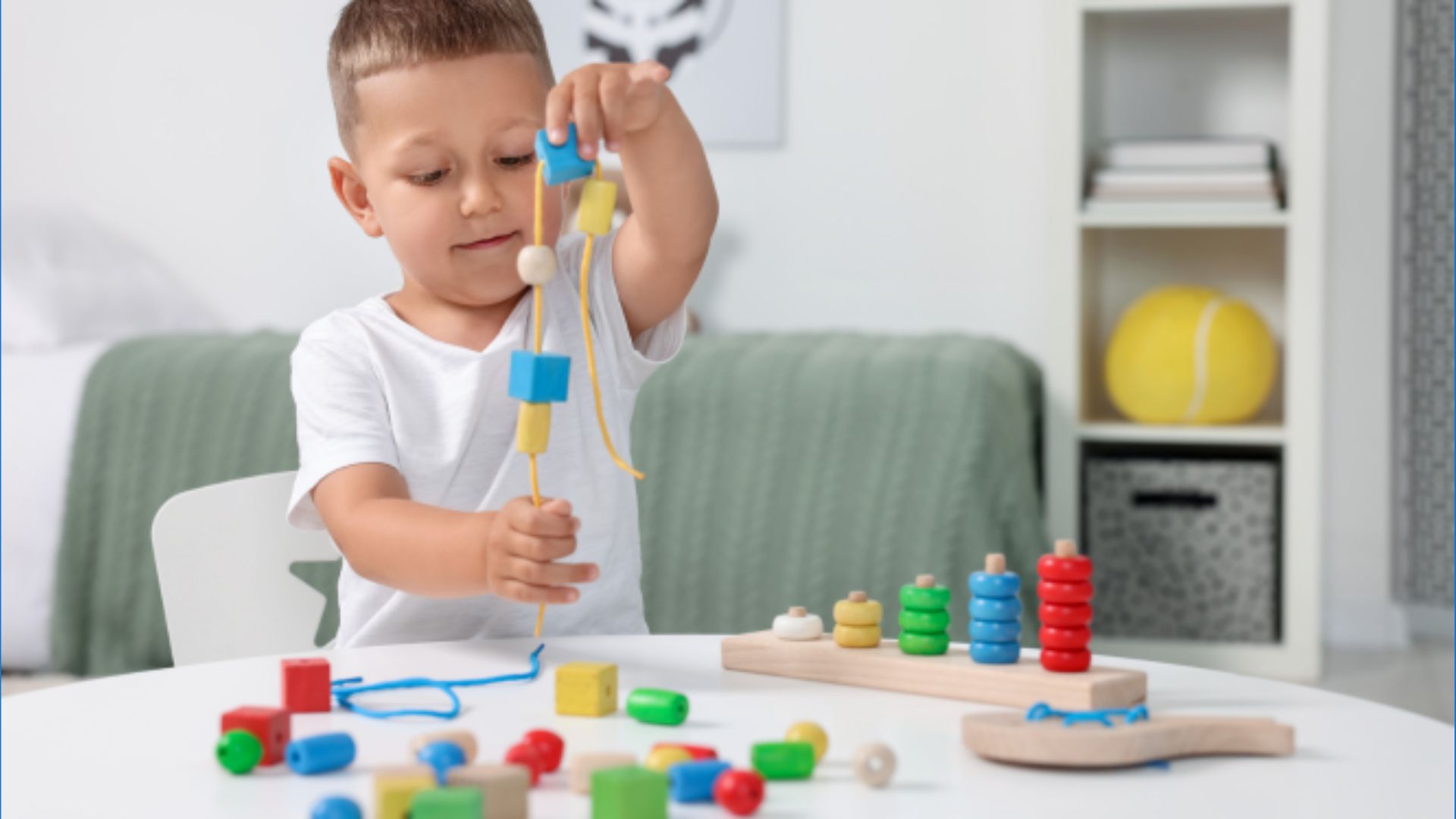 Preschool boy focusing on threading colorful beads onto a string, a fine motor self esteem activity for kids that celebrates completing small tasks independently