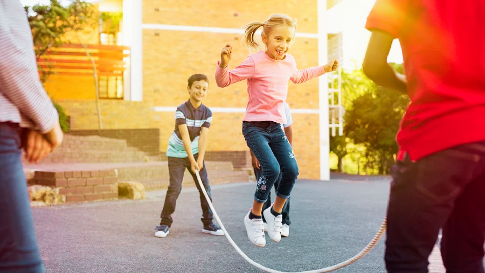 Children joyfully playing with a rope in a vibrant outdoor playground, surrounded by swings and slides.