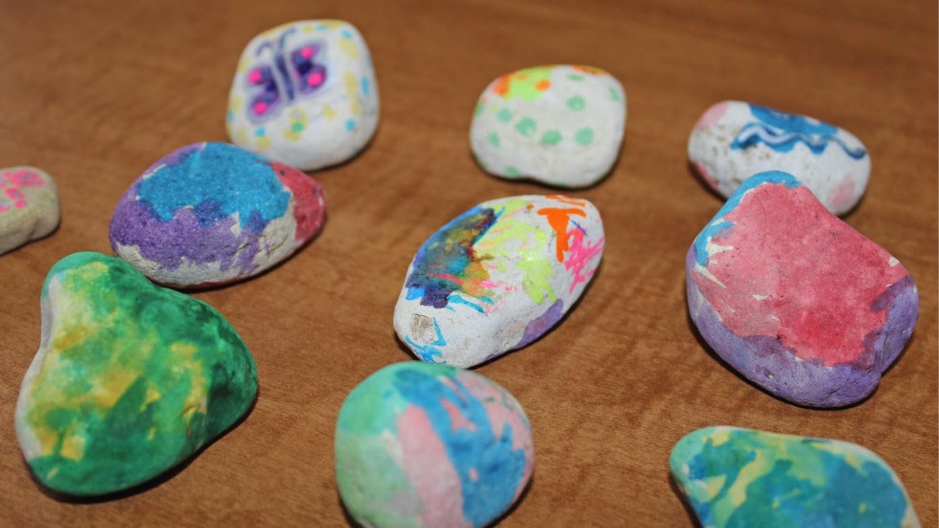 Colorful painted rocks with butterflies, swirls, and bright patterns rest on wooden table, creative, Summer Activities for Kids.