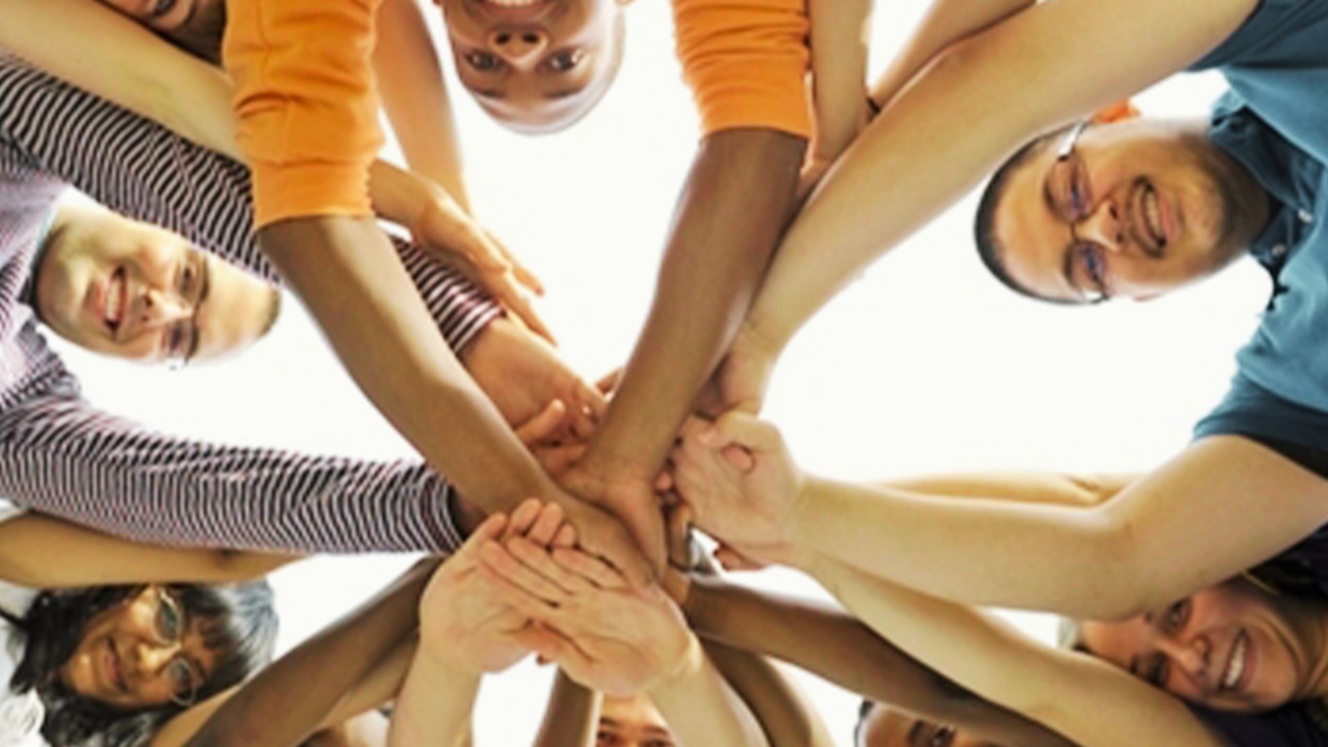 A diverse group of teens standing in a circle, joining hands together in a collaborative problem-solving activity.