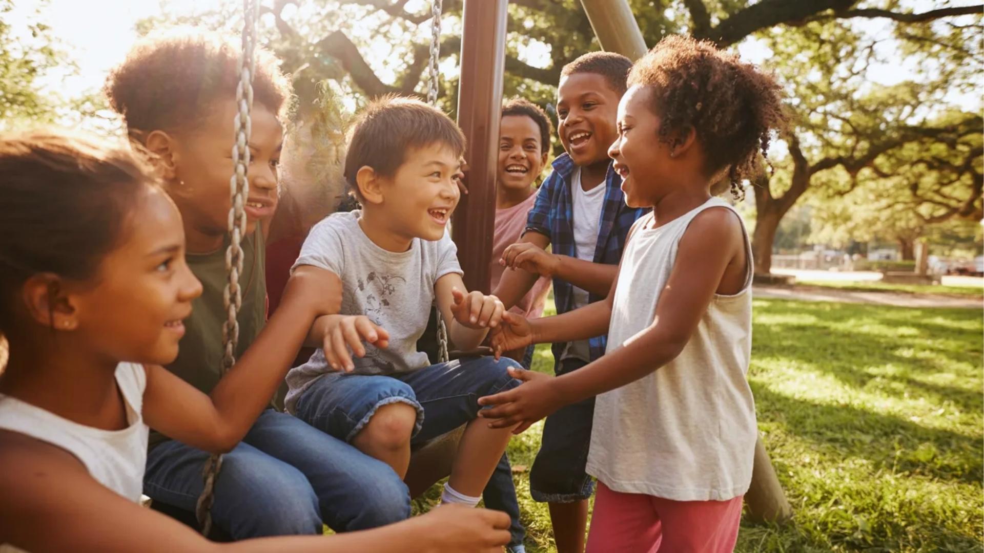 Diverse group of children playing together happily outdoors while showing inclusion, friendship, and shared joy