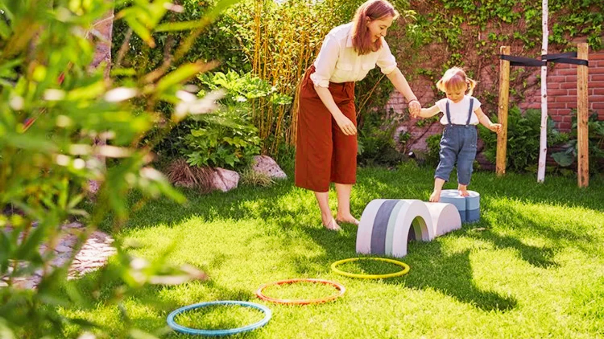 A woman and a child joyfully playing Obstacle together in a grassy yard under a clear blue sky.