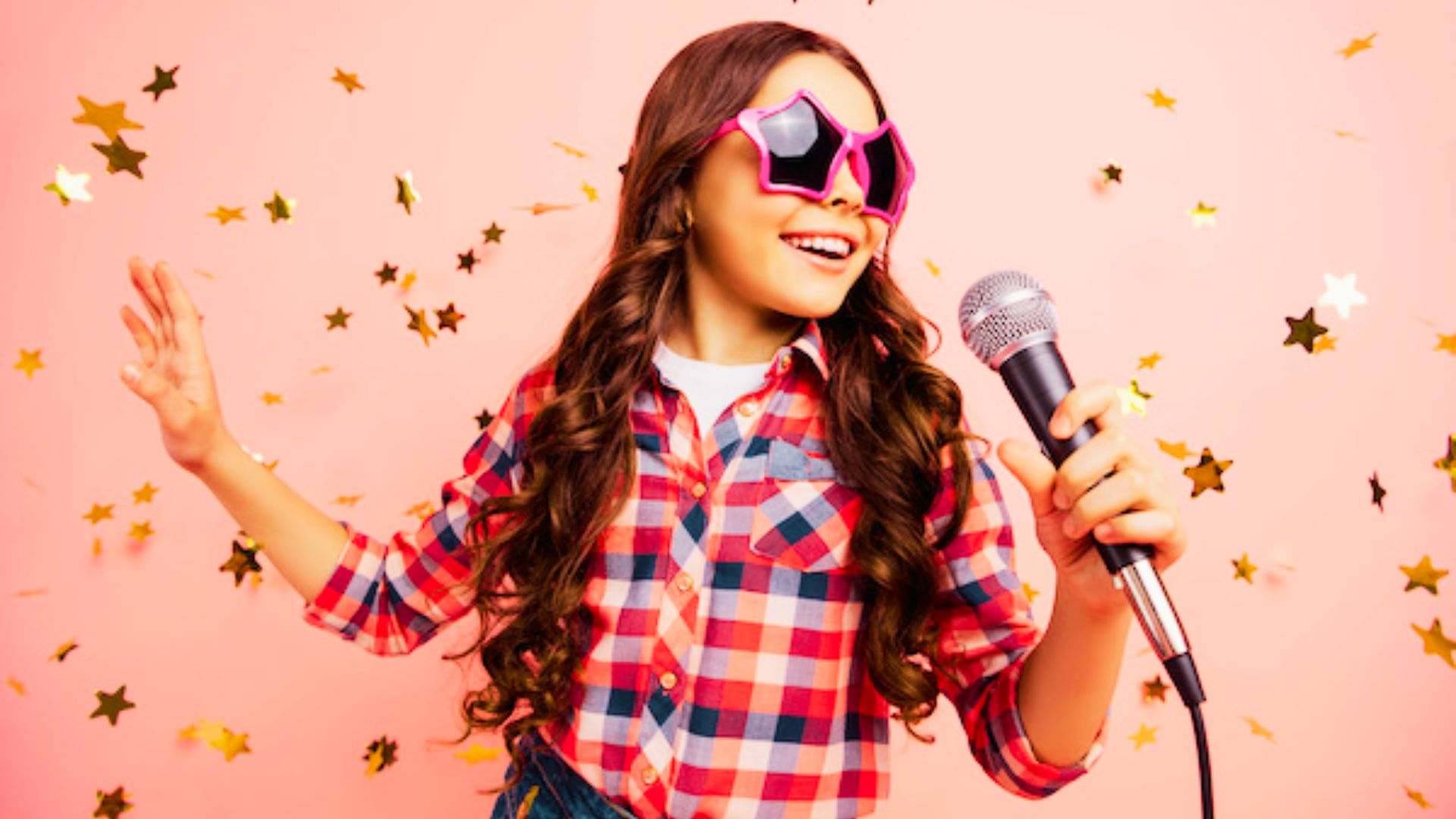 A girl wearing sunglasses holds a microphone while singing passionately on stage.