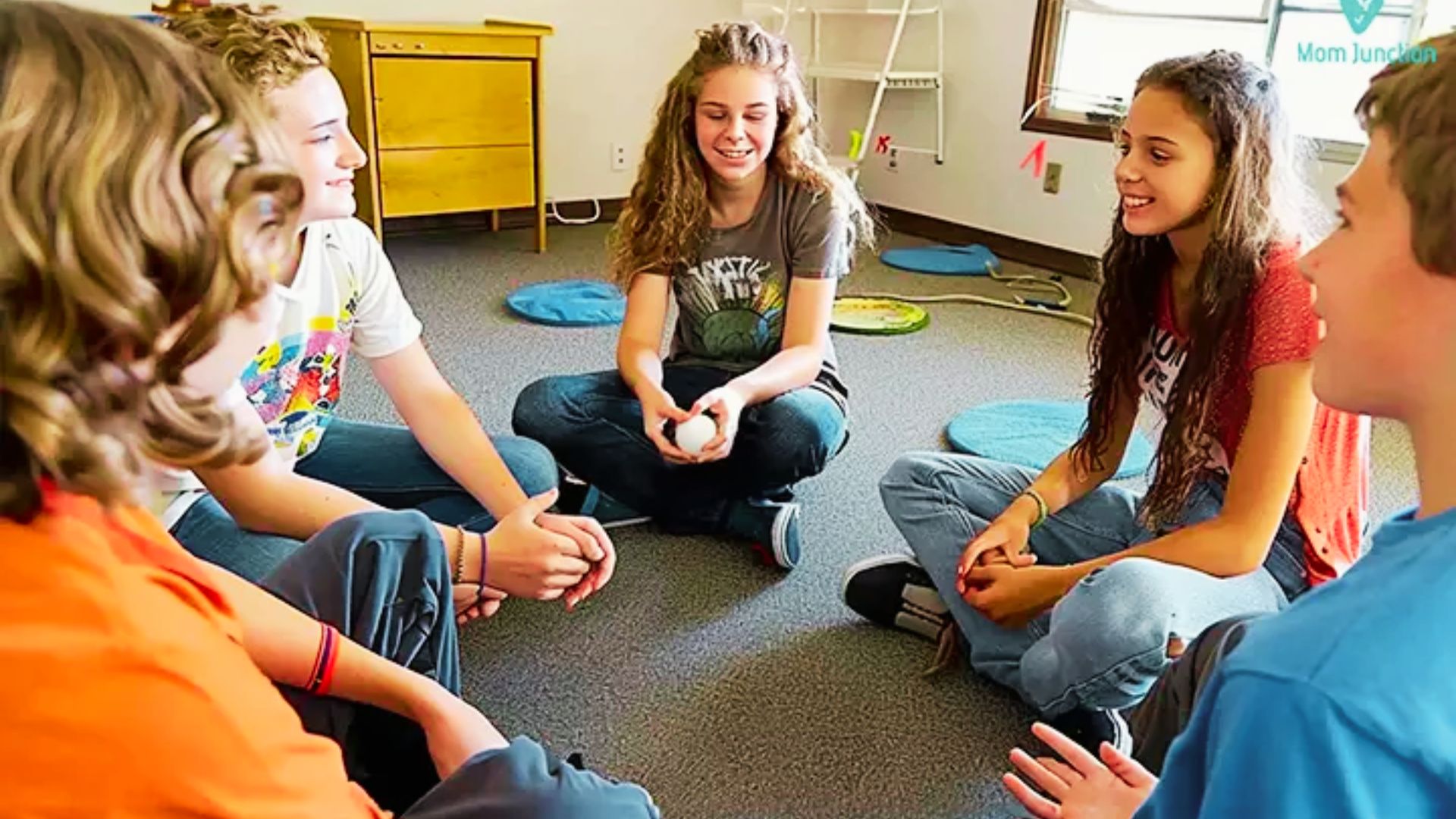 A group of young people engaged in discussion while sitting in a circle, participating in a problem-solving activity.