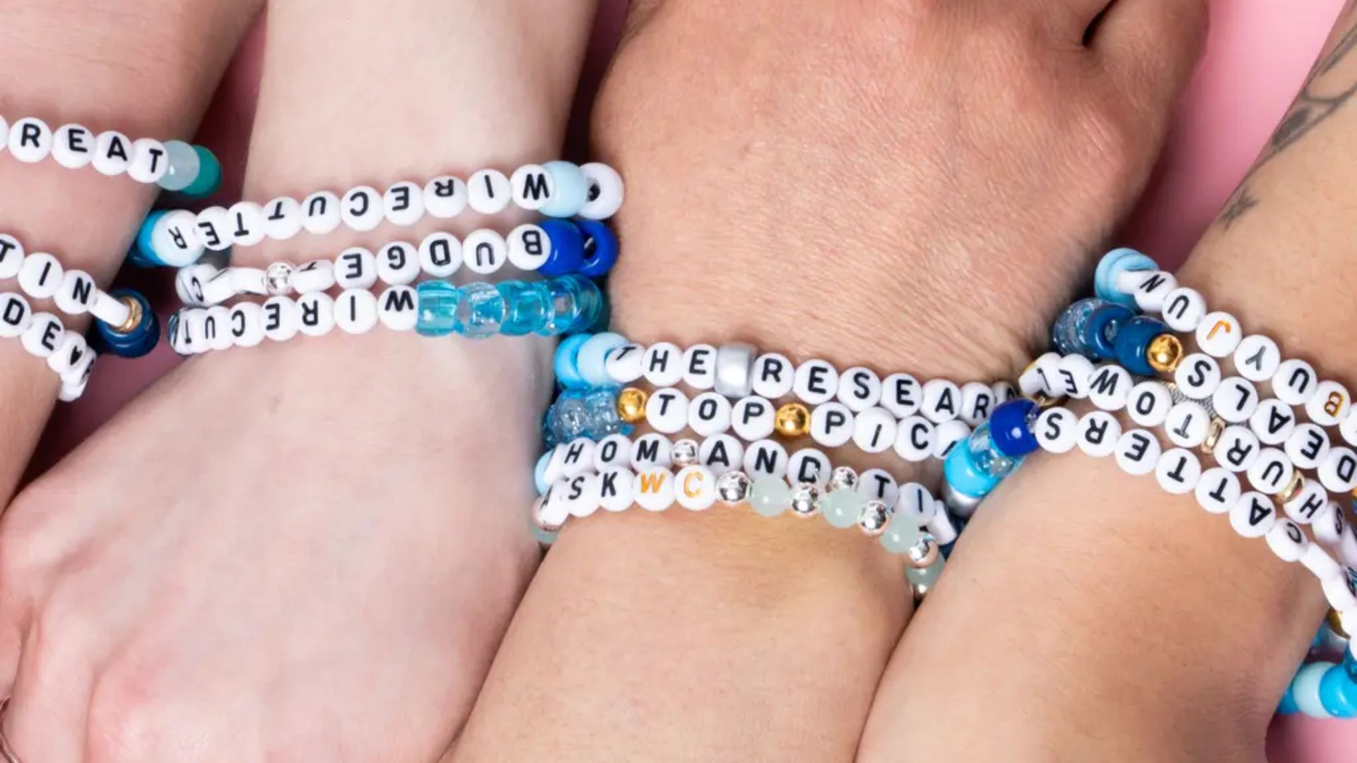 Close-up of children’s wrists wearing handmade letter bead friendship bracelets in blue and white, showing gift-giving and connection in a preschool friendship activity