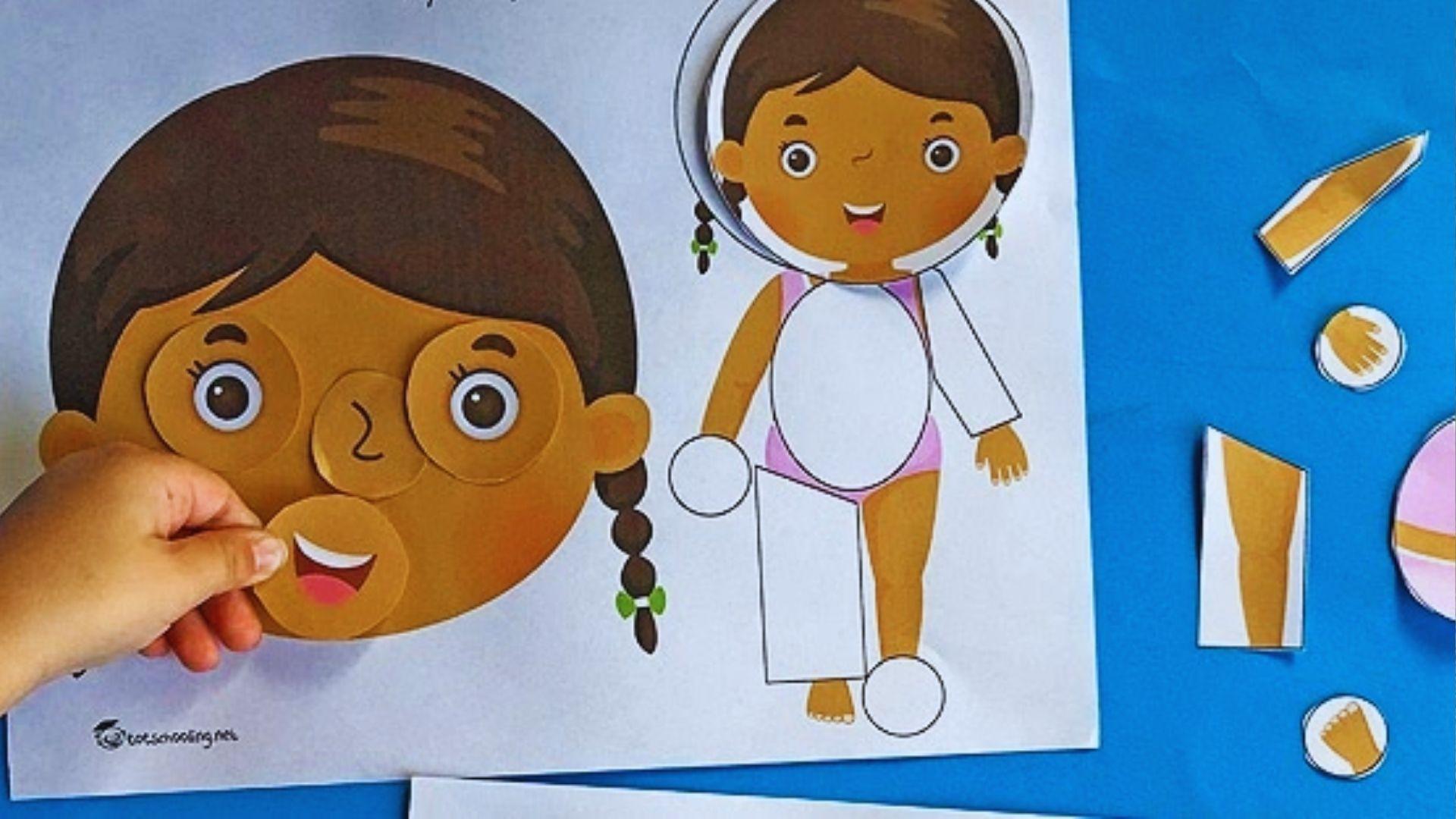 A child's hand holds a colorful paper cutout of a girl, showcasing creativity and playfulness.