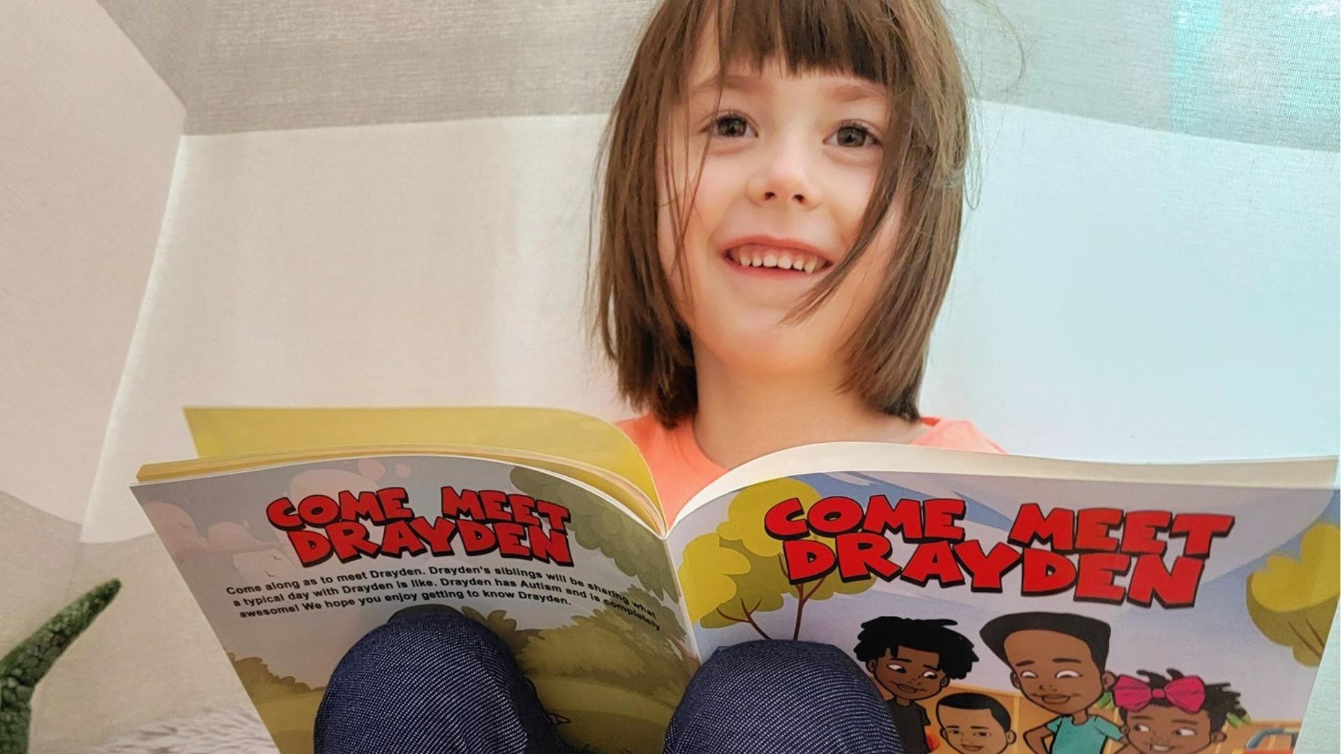 Smiling girl reads Come Meet Drayden book about autism in cozy reading corner, Activities for Autistic Kids.