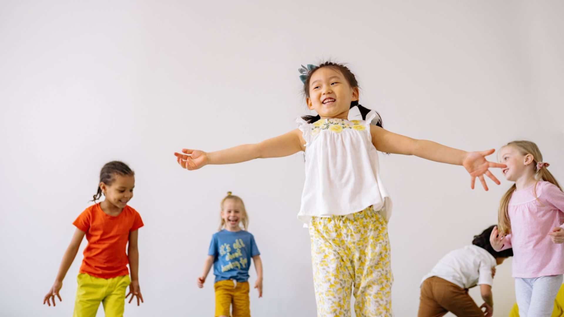 Group of diverse children running and laughing together, dancing and playing in an active indoor group game for kids