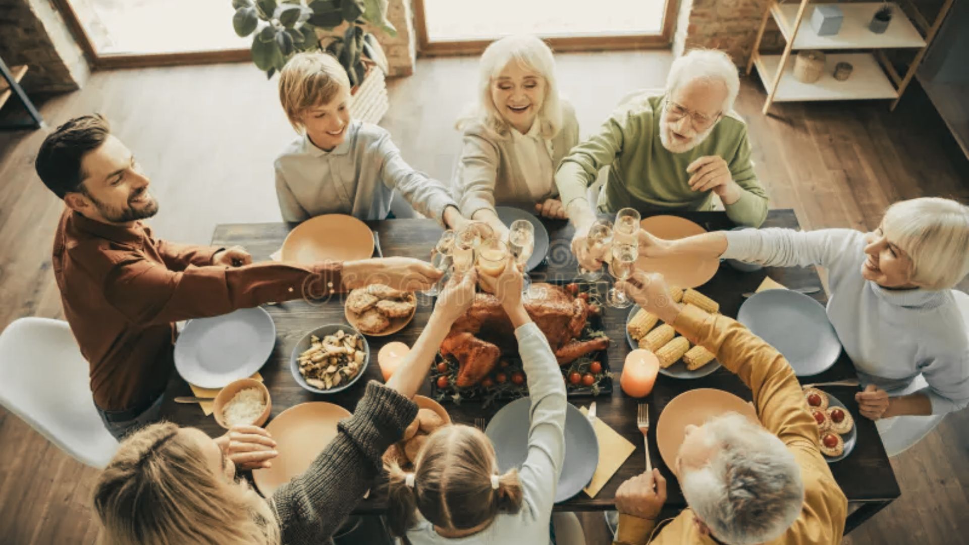 A Family joyfully toasting with glasses at a festive dinner table surrounded by food and decorations.