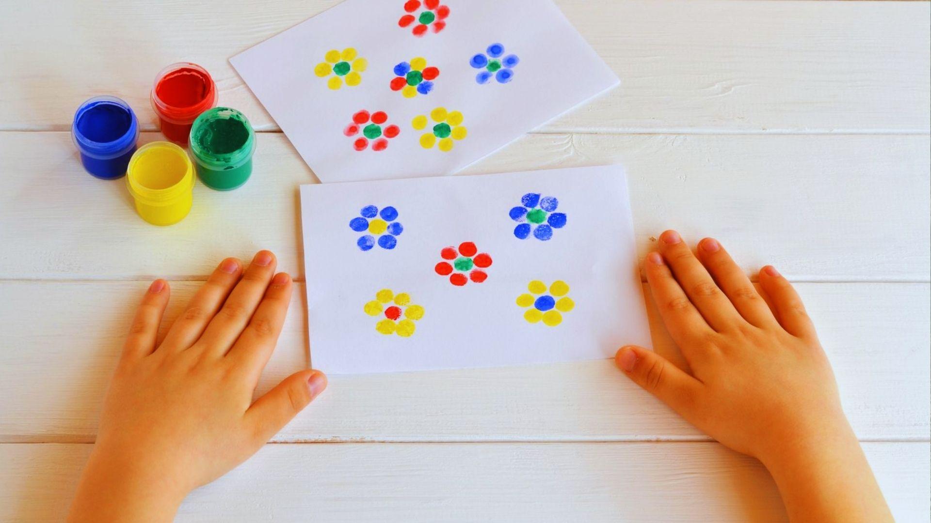 Hands holding a card adorned with vibrant, colorful flowers against a neutral background.