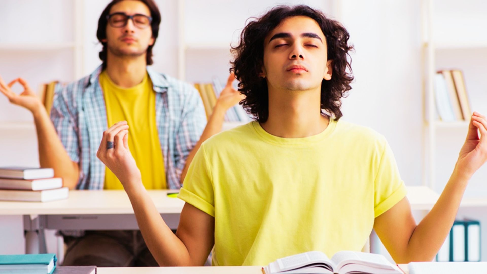 Two boys sitting cross-legged and in a peacefully in a bright classroom setting.
