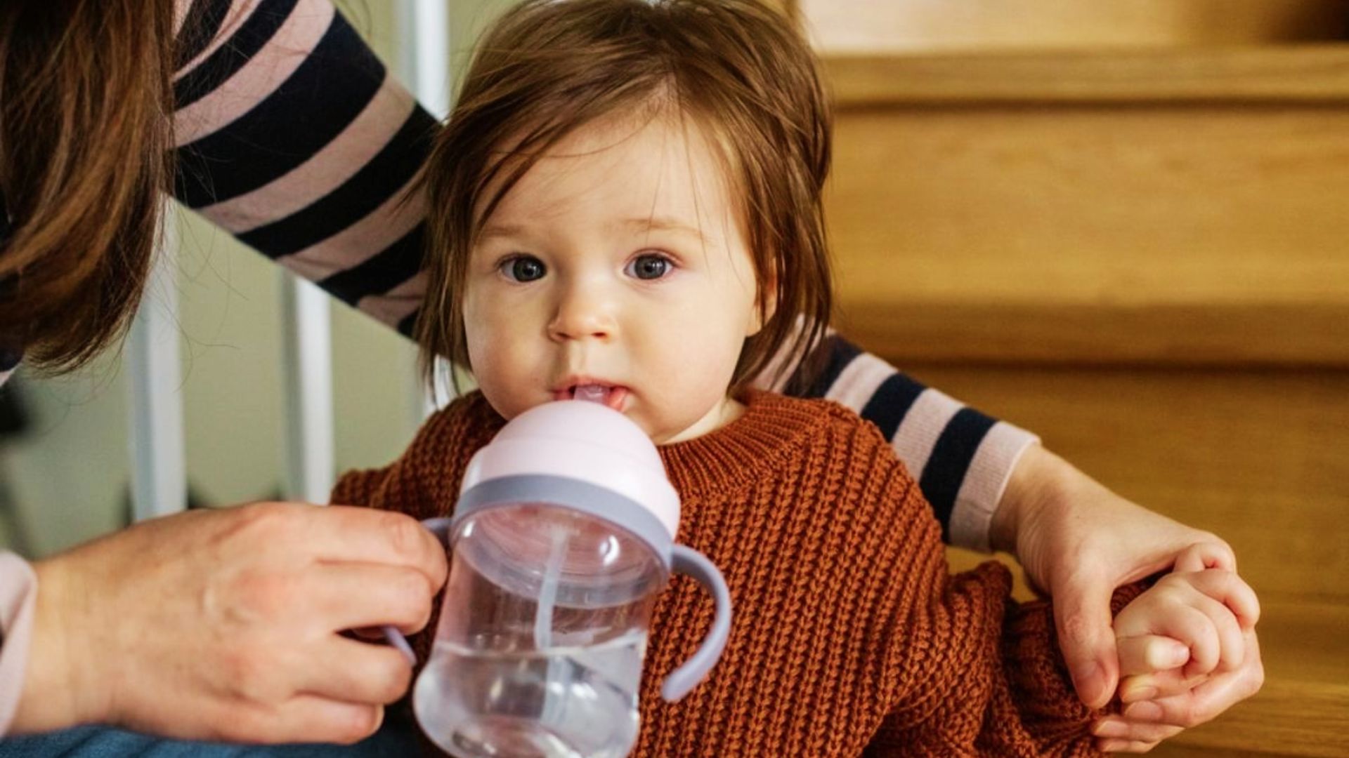 A woman gently feeds a baby with a bottle, highlighting the importance of proper feeding methods for dental health.