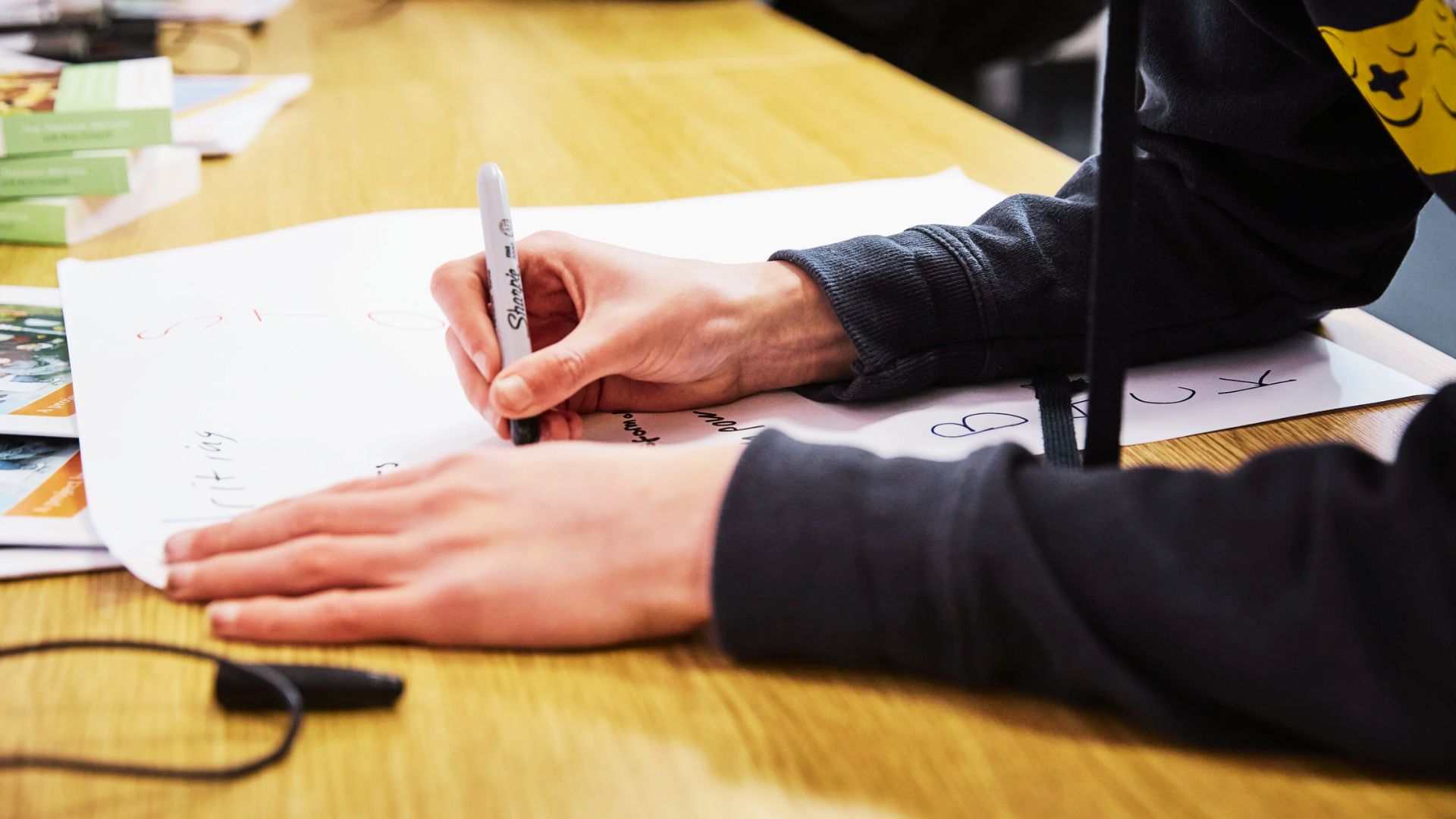 A person writing on a sheet of paper with a pen, focused on their task.
