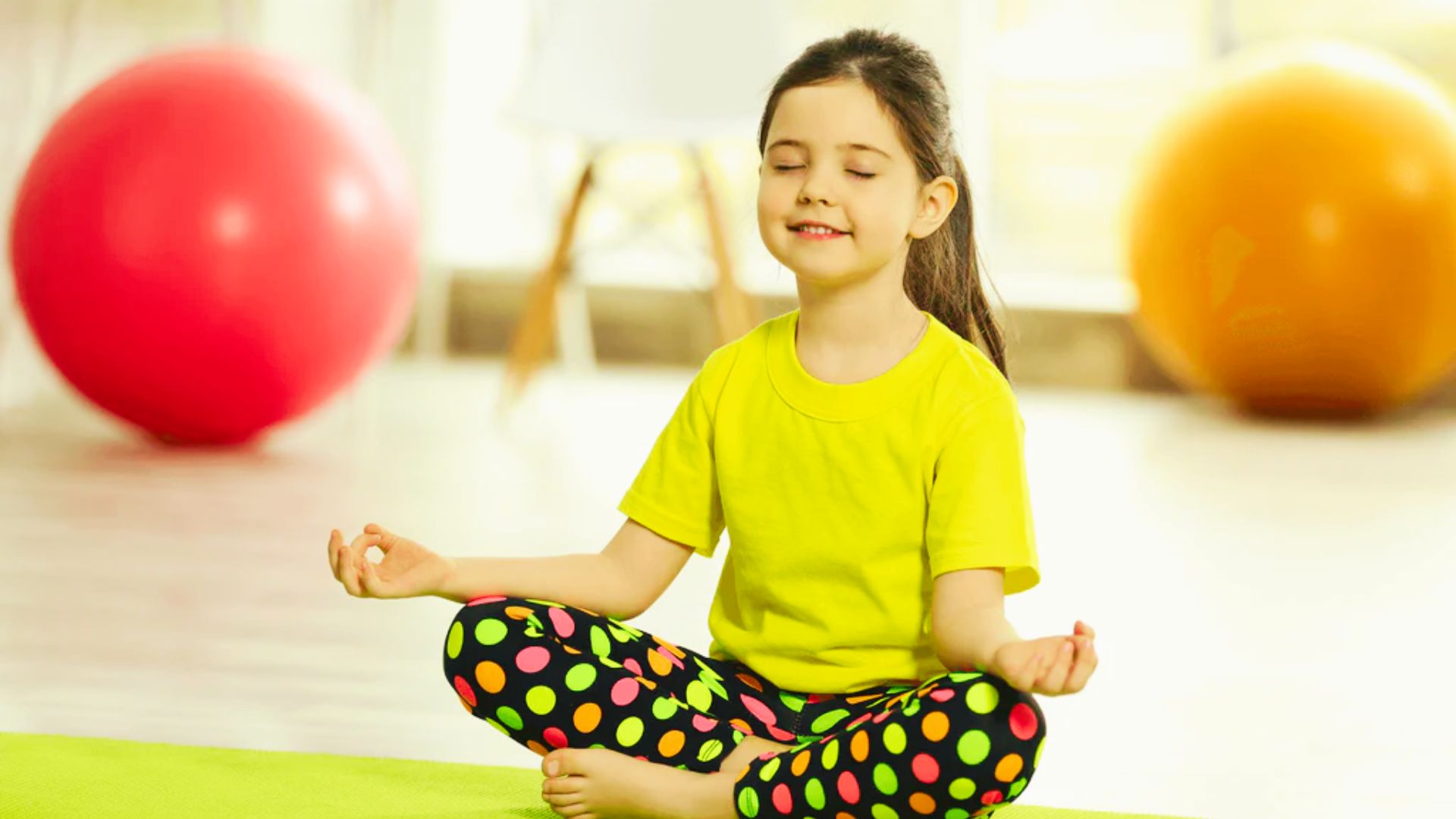 A young girl sits cross-legged on a yoga mat, focused and ready for her practice.