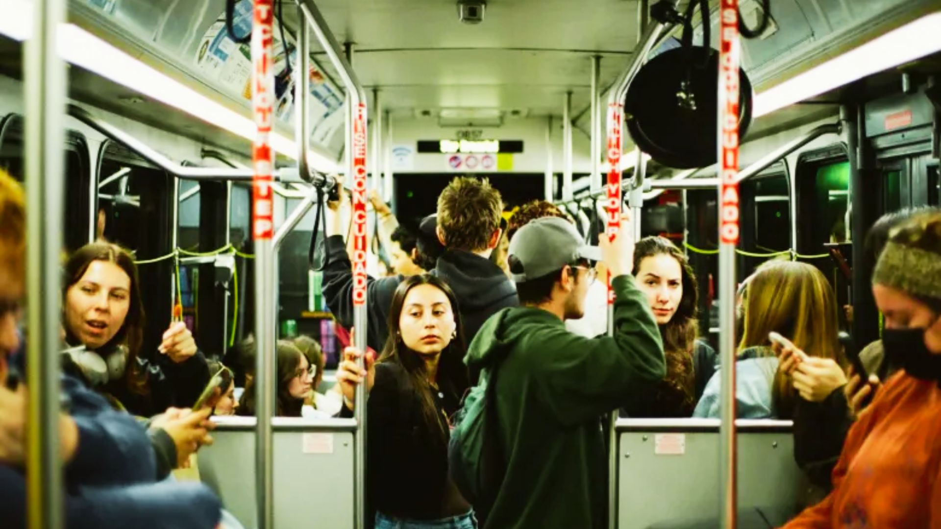 A group of people on a subway train, each focused on their phones, surrounded by the interior of the train.