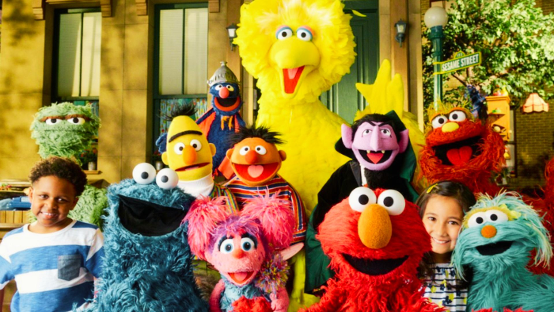 A group of children happily posing with colorful Sesame Street characters, celebrating the joy of educational entertainment.