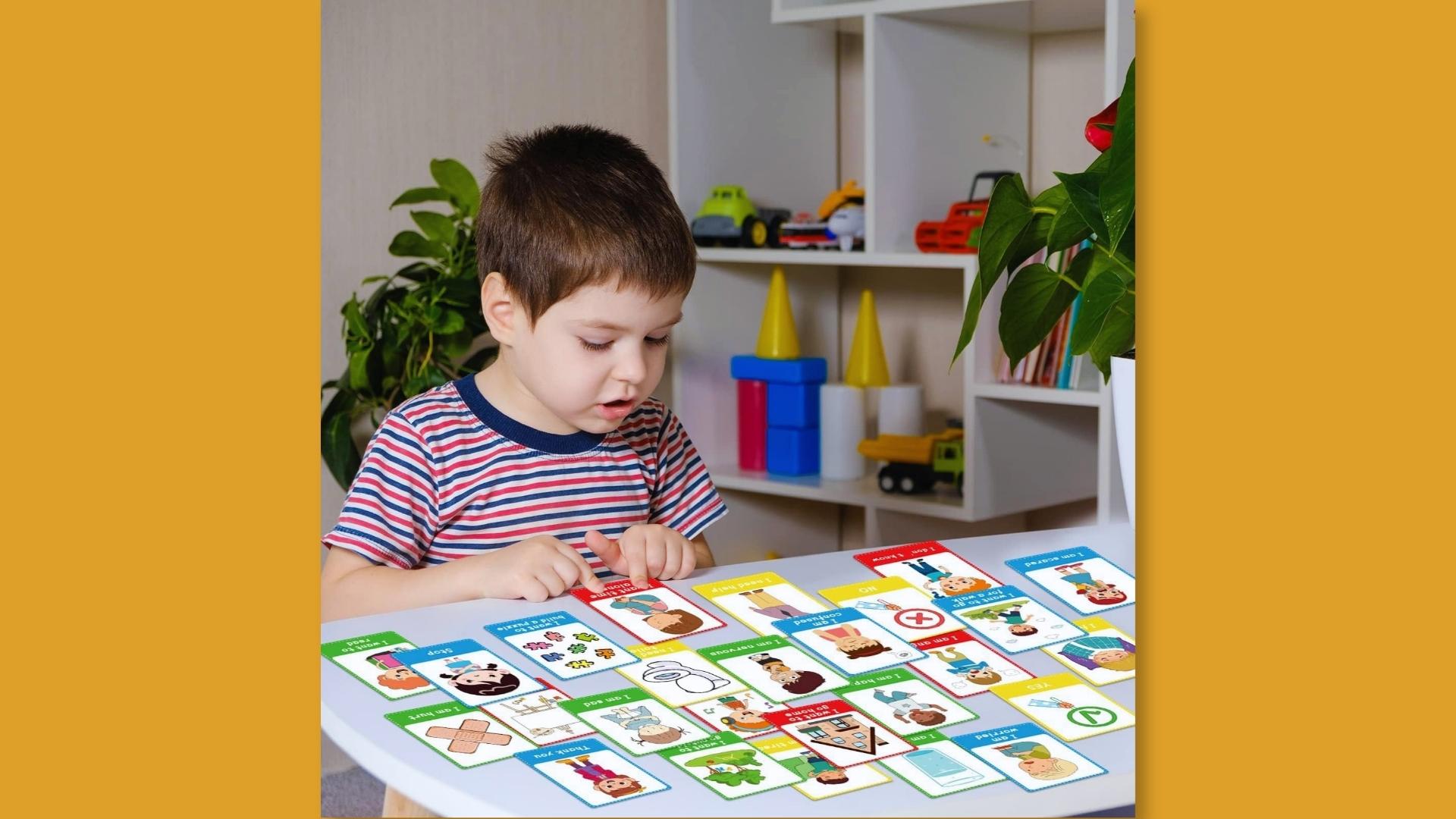 Boy uses colorful emotion cards at table to identify feelings, communication support tools, Activities for Autistic Kids.