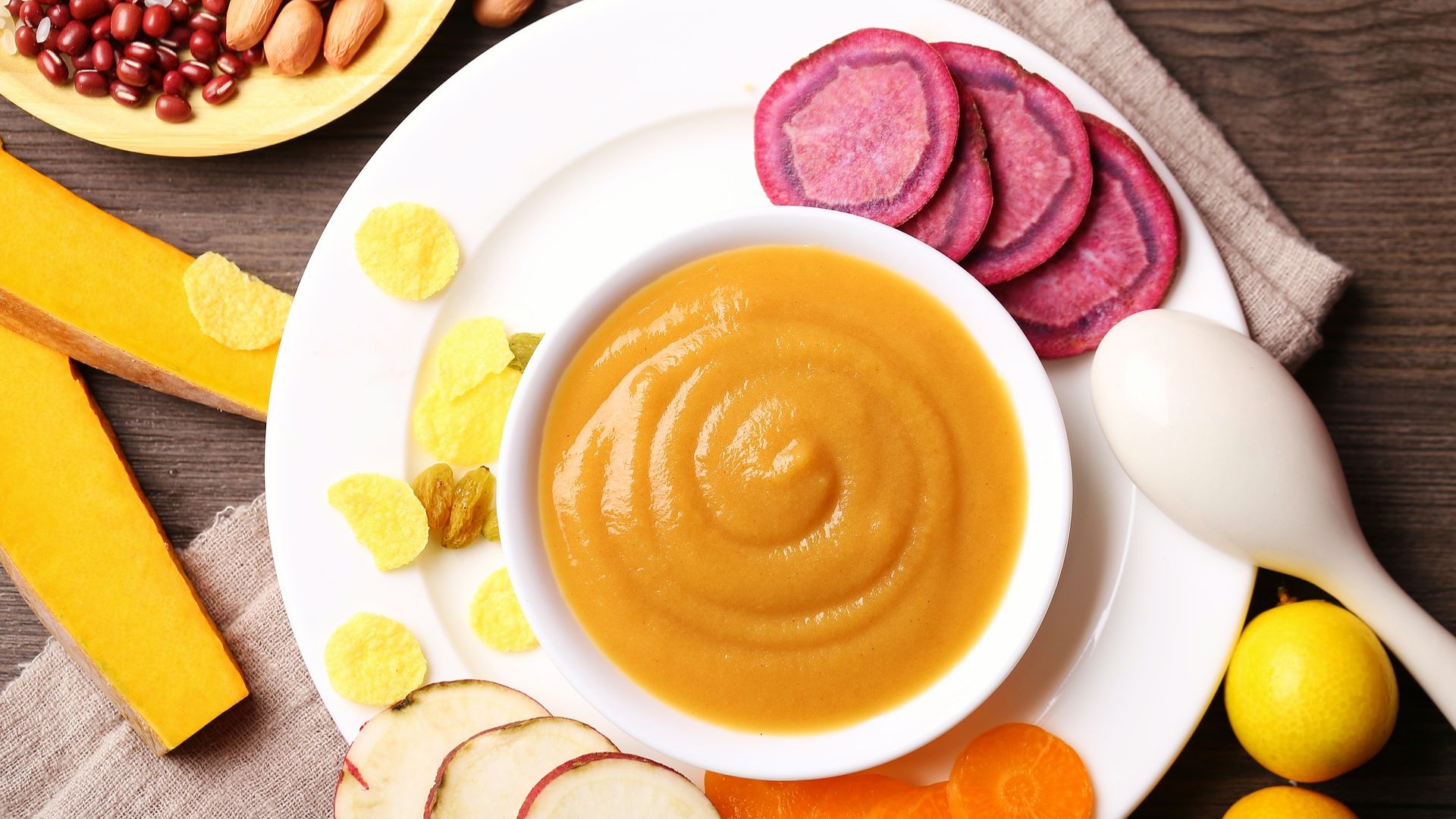 A bowl of pureed soup featuring carrots, apples, and assorted vegetables, designed for easy consumption.