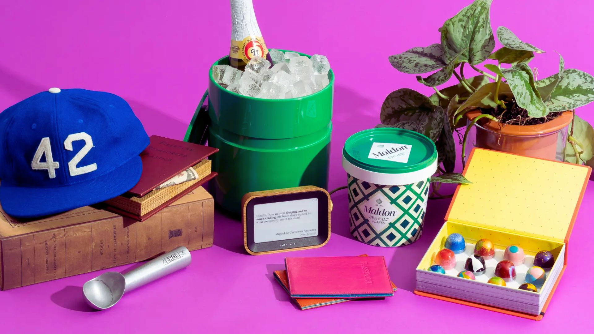 A pink table displays a hat, a book, a water bottle, a plant, and a cup, creating a cozy and inviting scene.