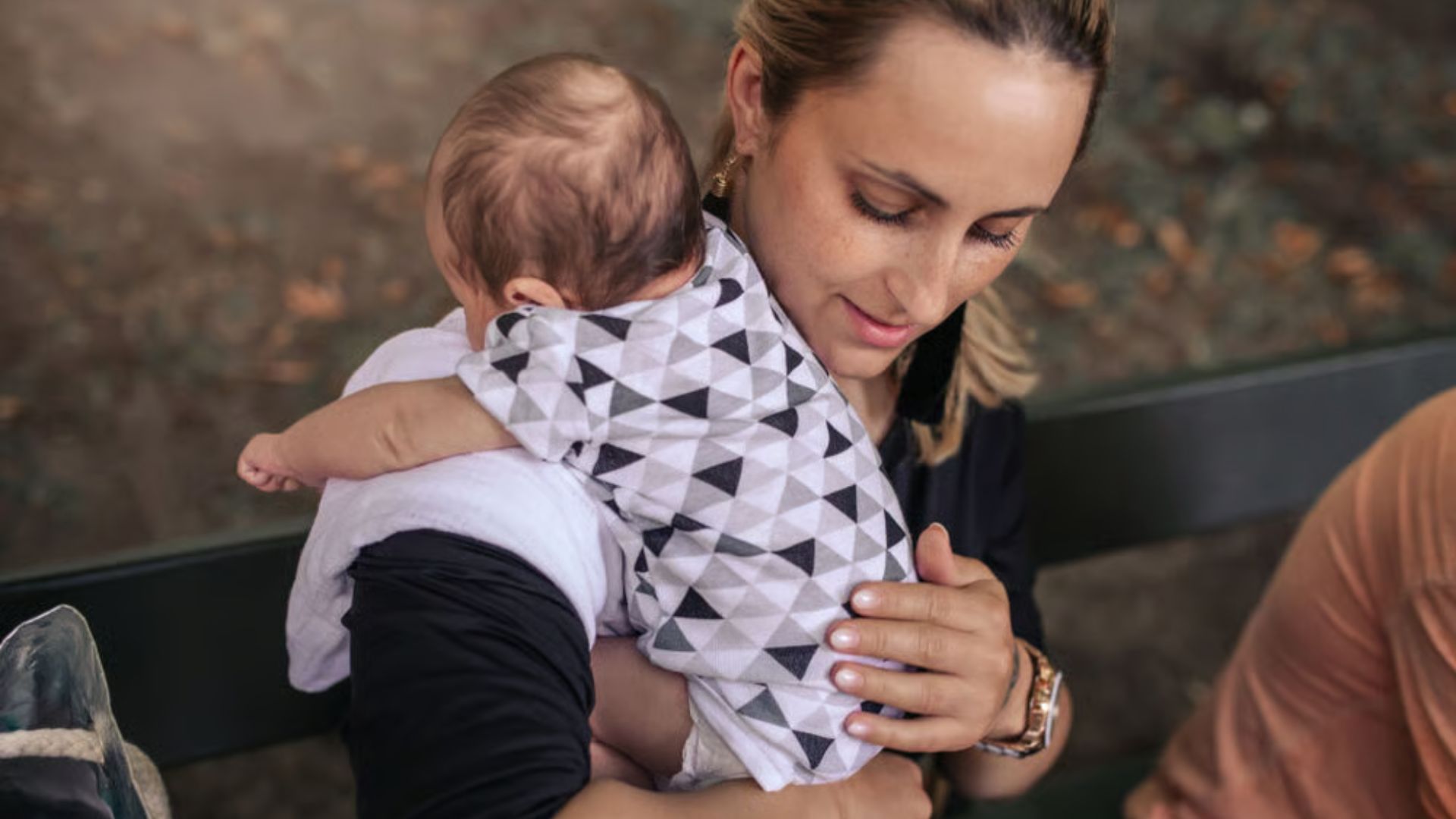 Mother using the shoulder hold: Baby rests against the chest with head on shoulder, while adult's hand supports the baby's head, neck, and bottom.