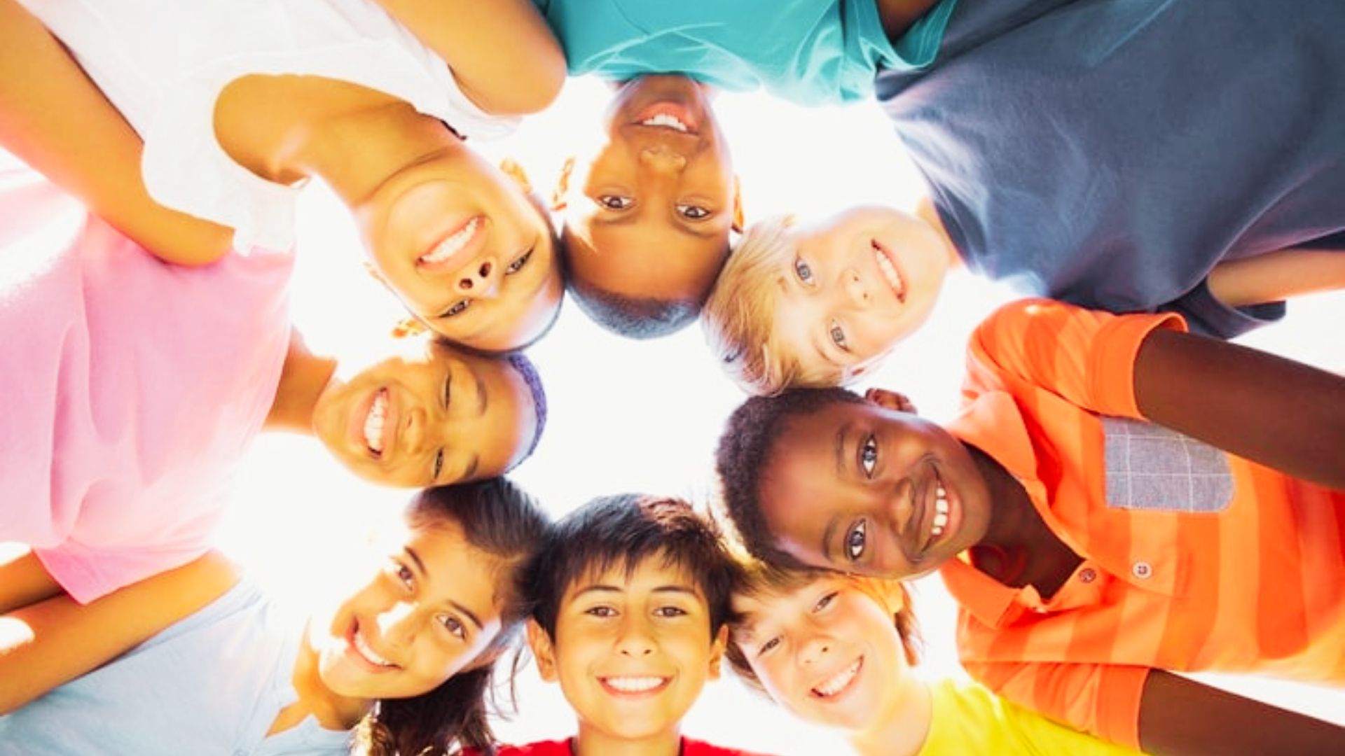 A group of children standing among teenagers, engaged in a collaborative problem-solving activity.