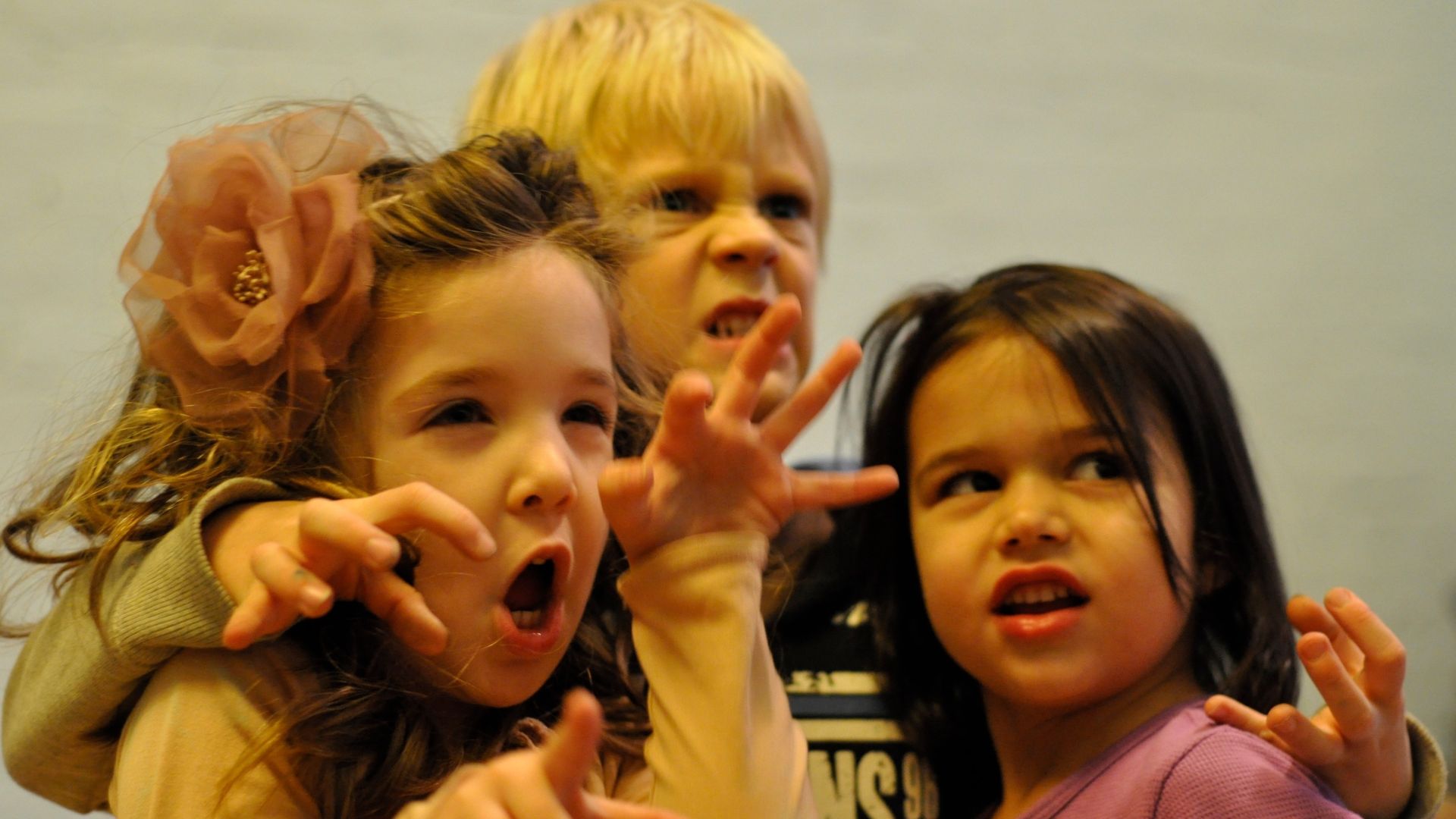 Three preschool friends making funny faces and hand gestures together, expressing joy and building emotional connection in a playful friendship activity for kids