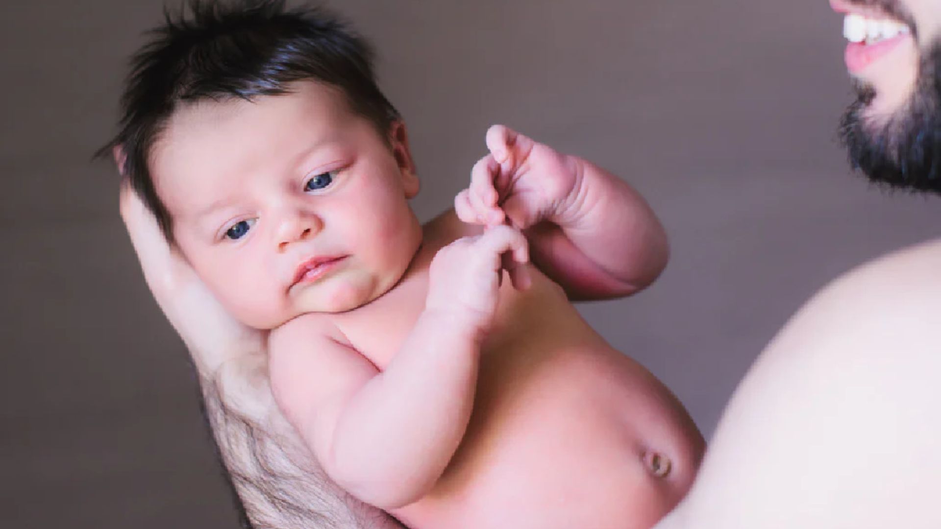 Father shows the newborn cradle hold. Babyโs head and neck are fully cradled in the hand, keeping the spine aligned and supported.