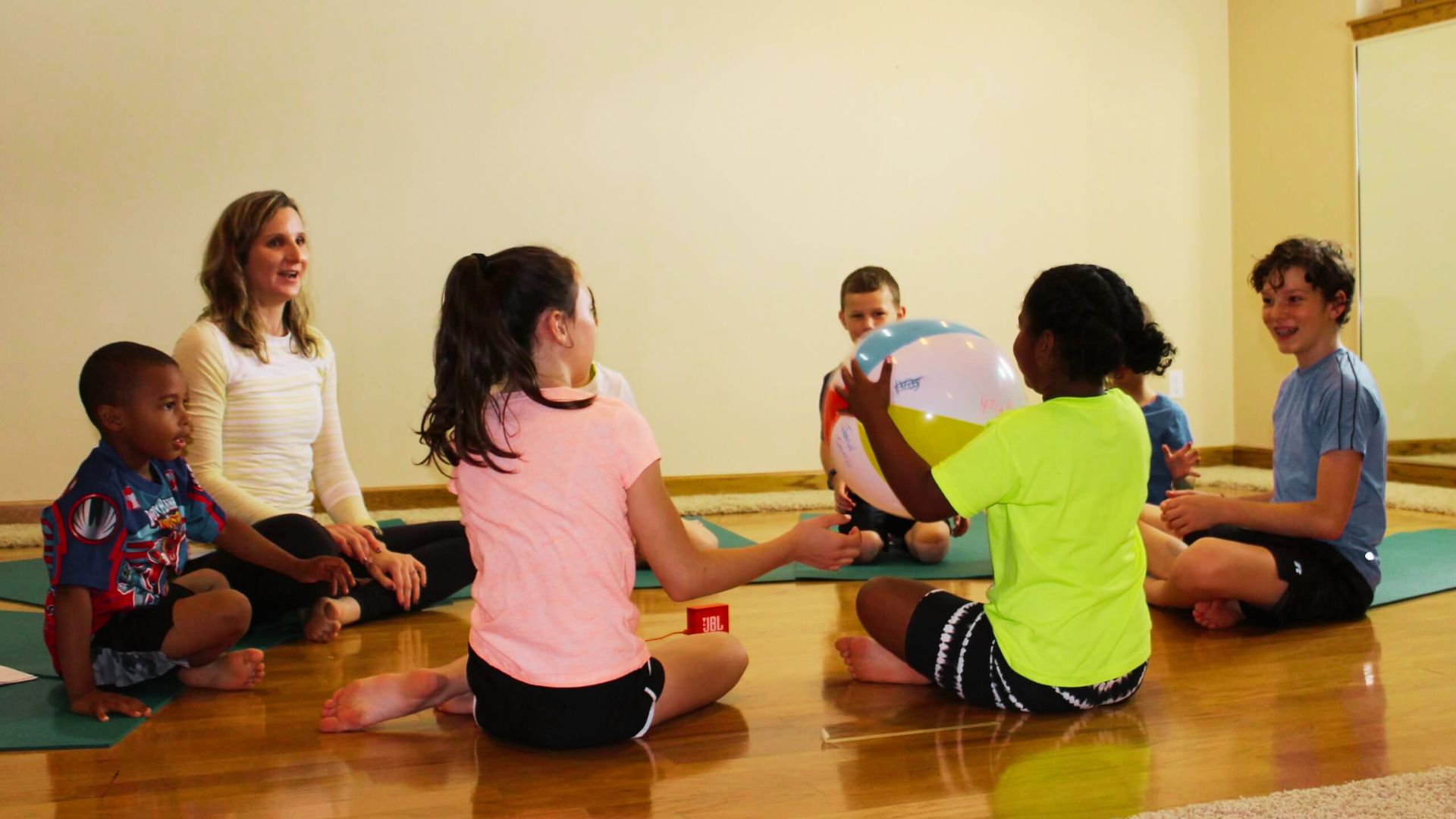 A group of children playing silent ball game on the floor, focused and engaged in their class activities.