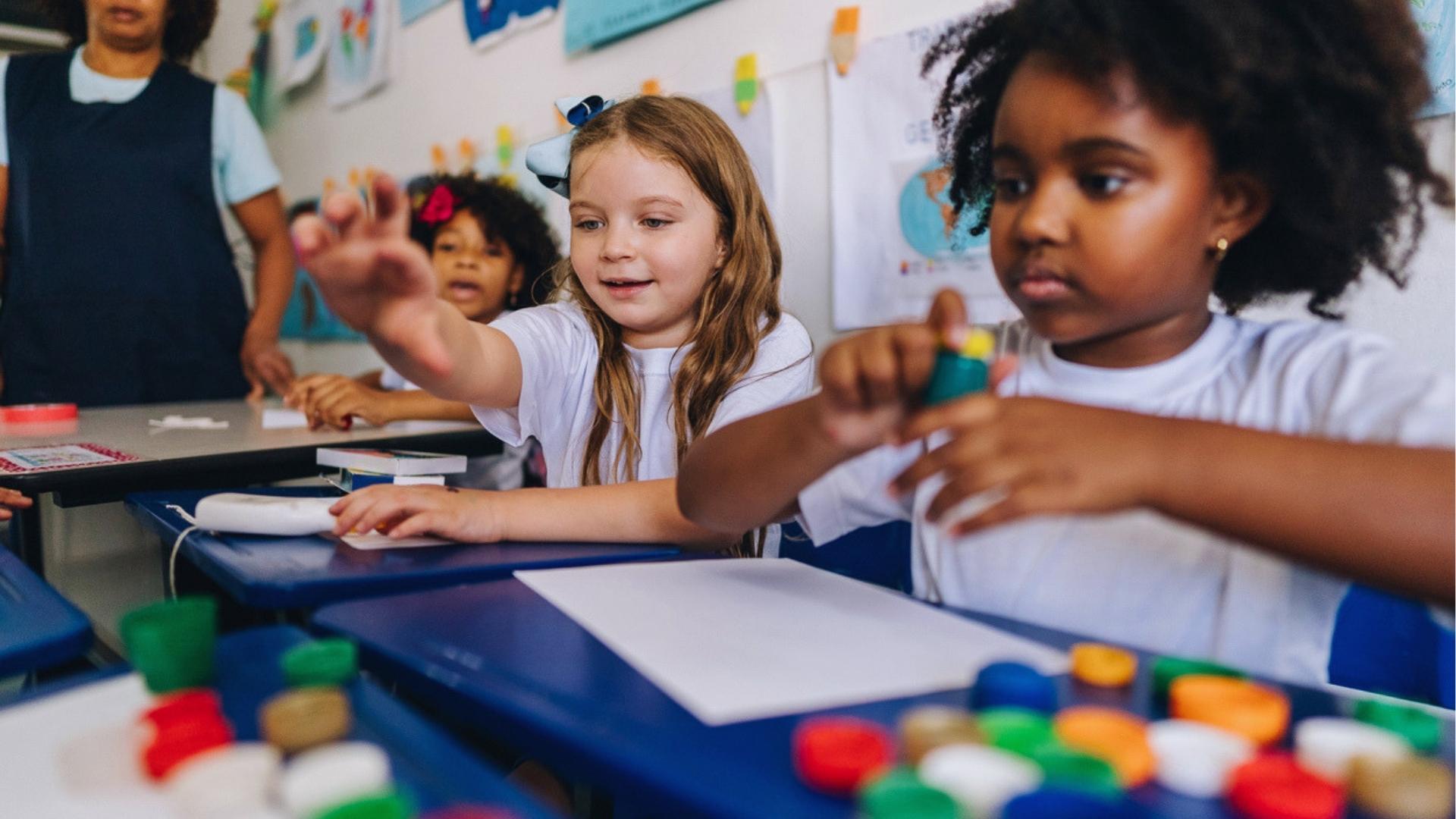 Children in classroom creating with glue sticks and paper