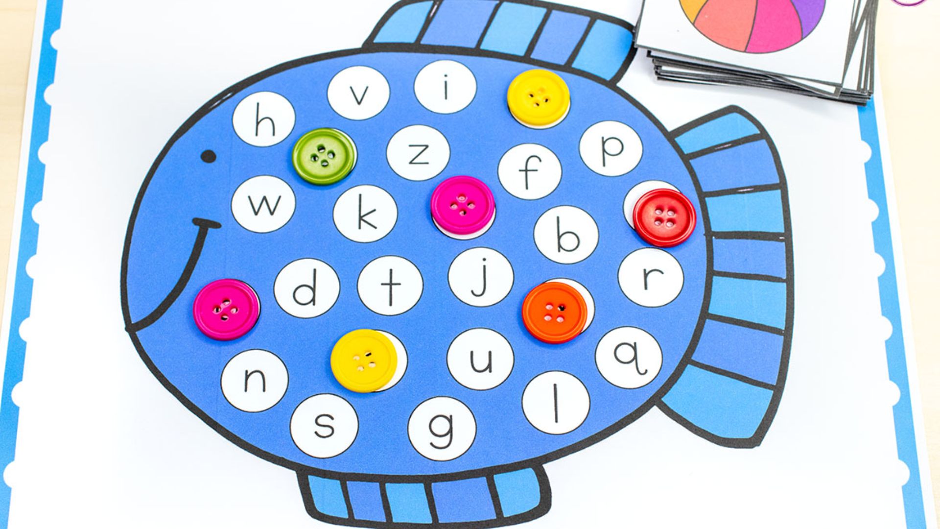 Blue fish printable with lowercase letters in circles. Colorful buttons cover letters as child matches from picture cards.