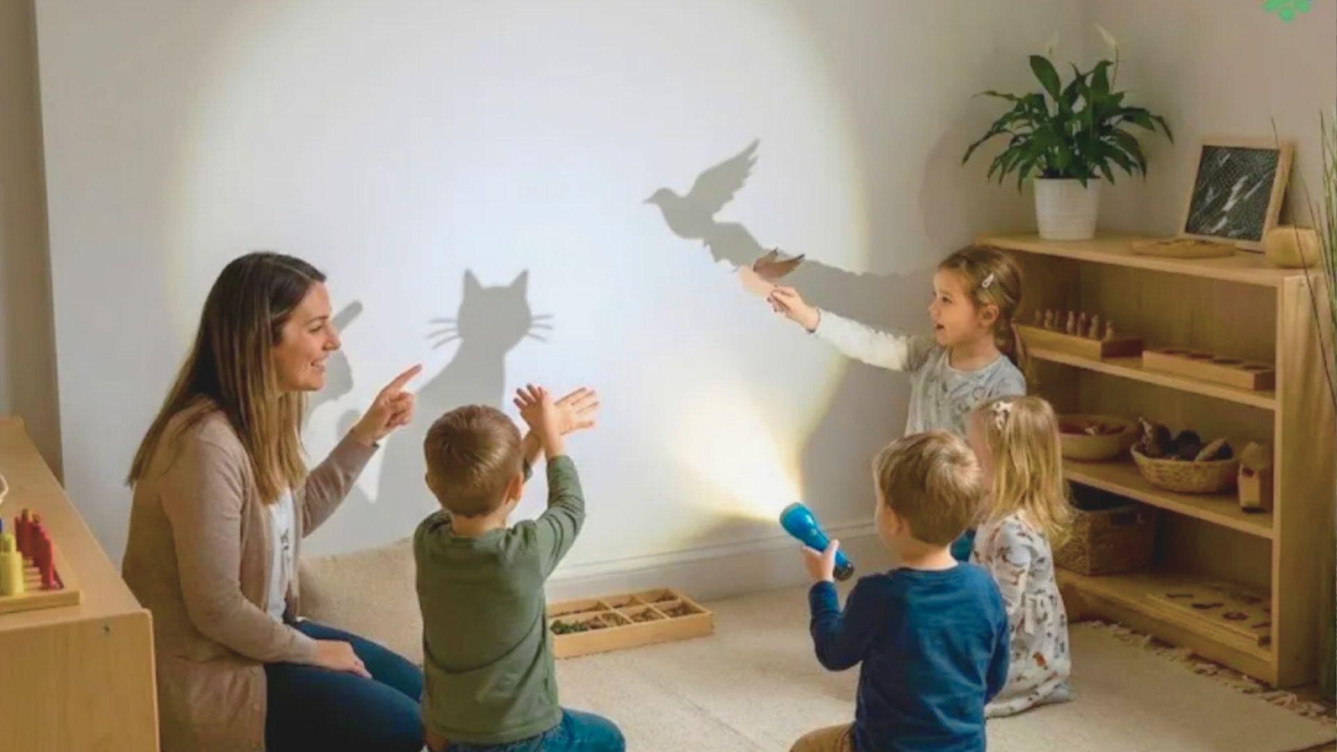 A woman and children joyfully interacting with a playful shadow projection on the ground.