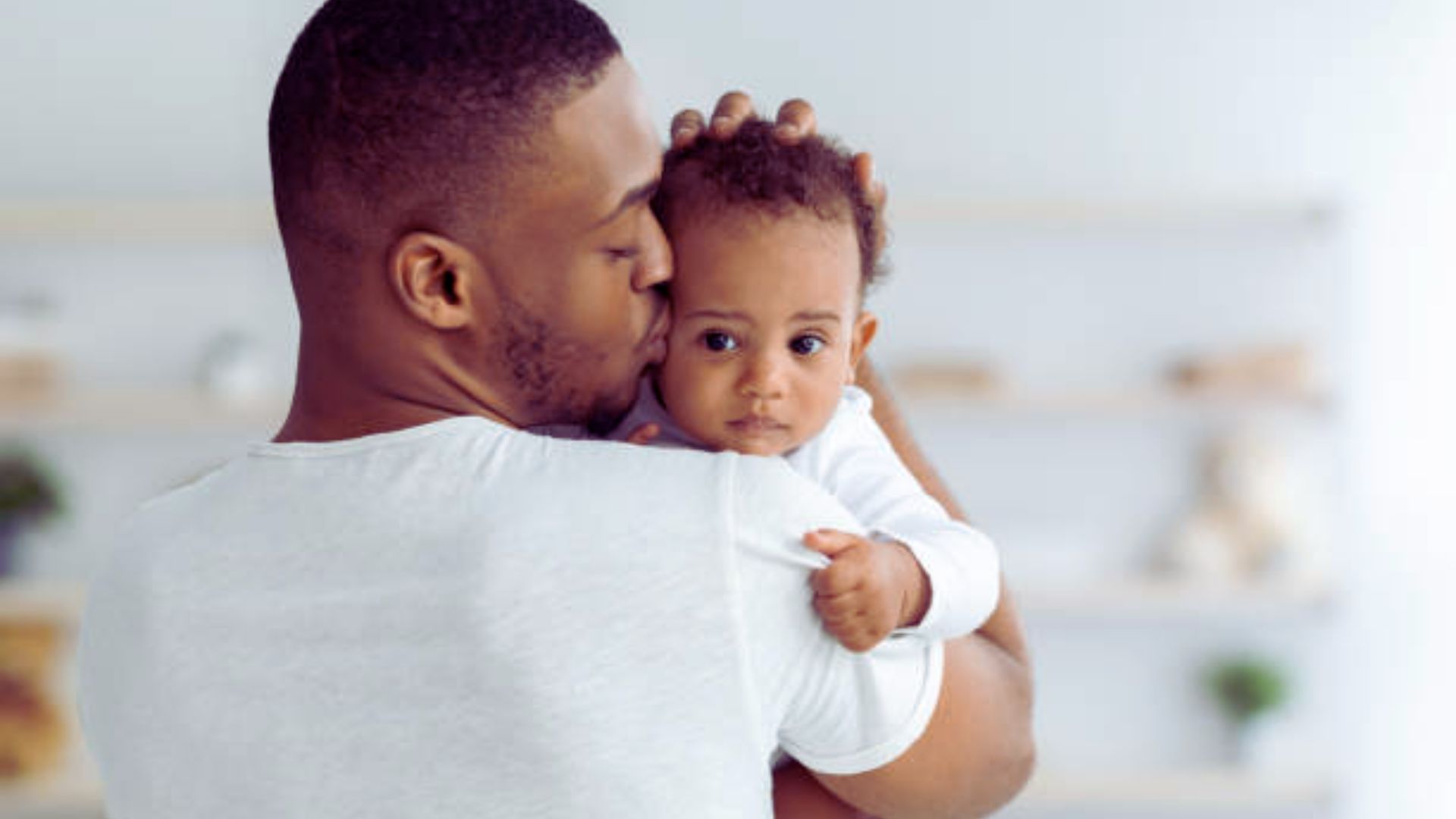 A man gently cradles a baby in his arms, showcasing a tender moment of care and affection.