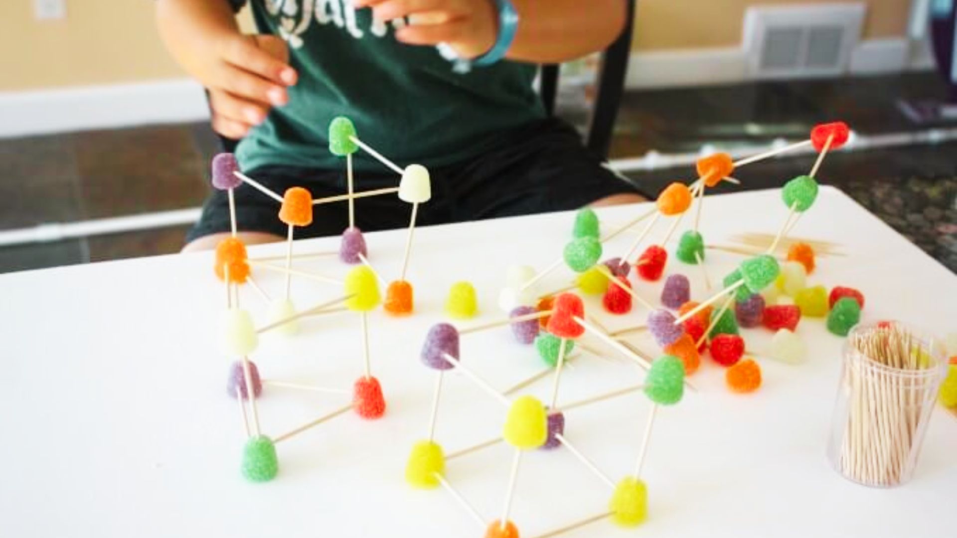 A child constructs a vibrant structure using colorful sticks, showcasing creativity and playfulness.