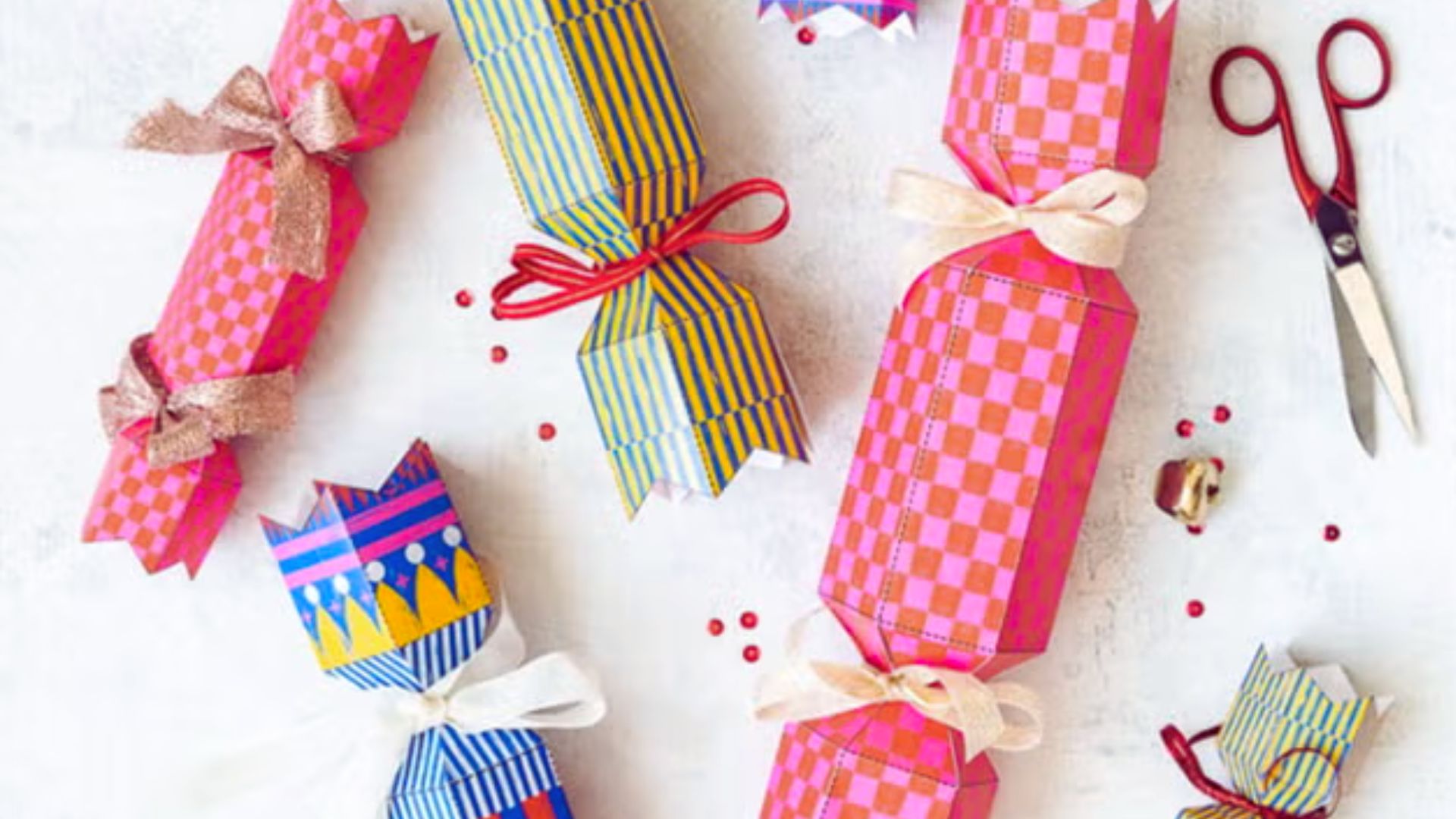 Christmas crackers adorned with colorful ribbons and a pair of scissors placed nearby for opening them.