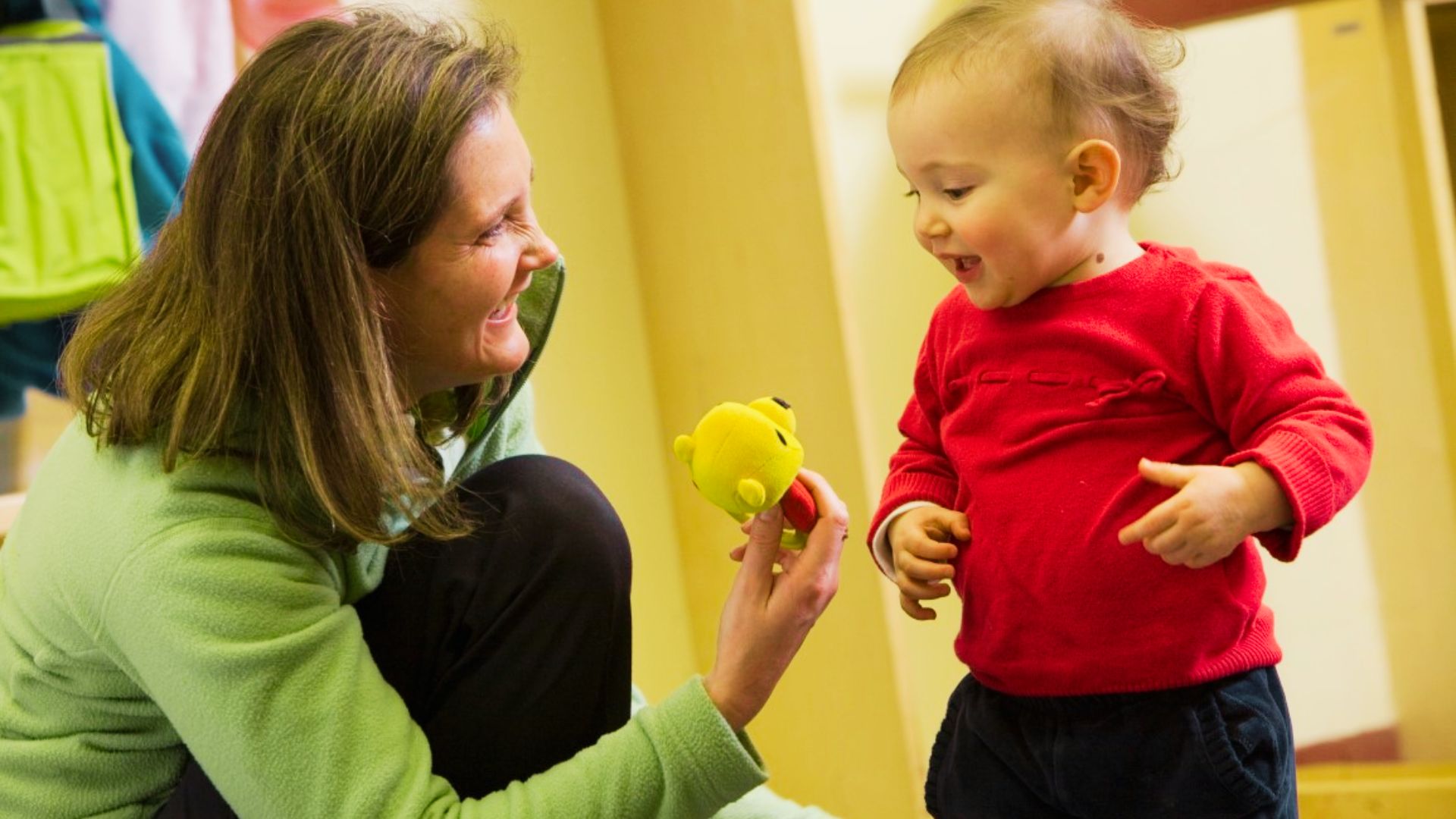 A woman and a child joyfully Role playing with colorful toys in a bright, cheerful room.