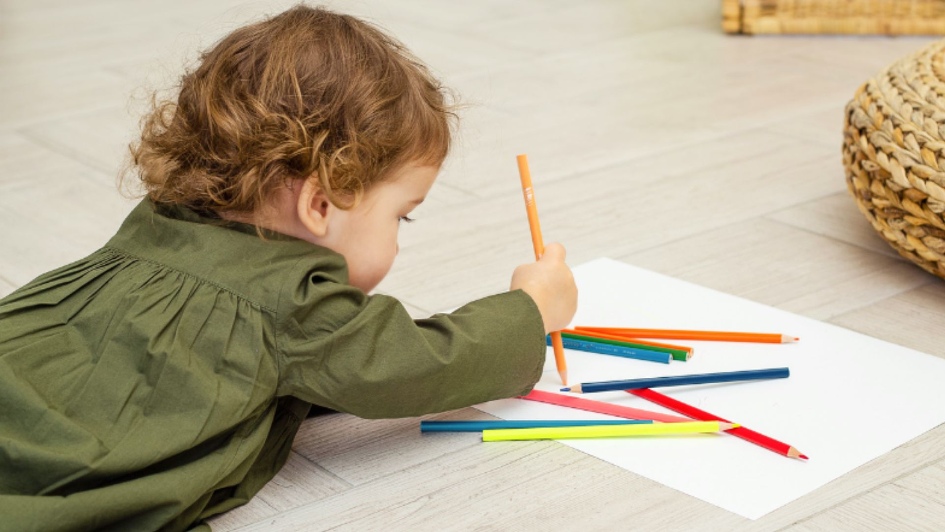 A 18 Month boy is engaged in play on the floor, surrounded by colorful pencils as he explores his creativity.