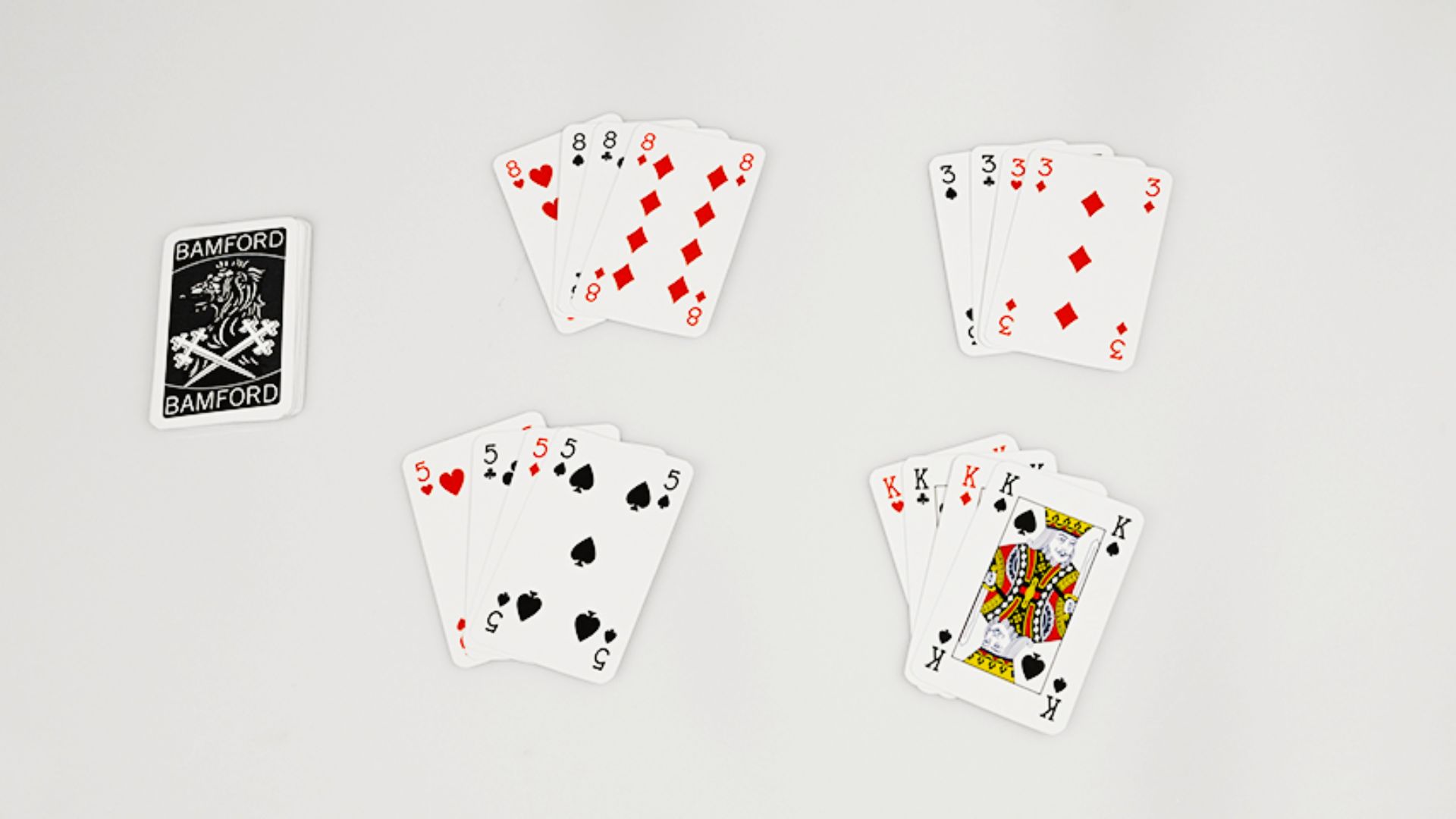 Playing cards are fanned out on a white surface, showcasing their distinct designs and suits.