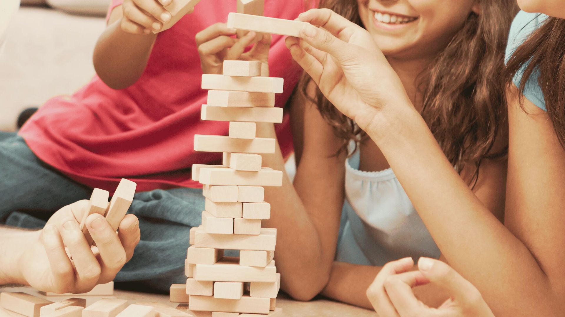 A group of children joyfully playing together, building structures with colorful wooden blocks on a play mat.