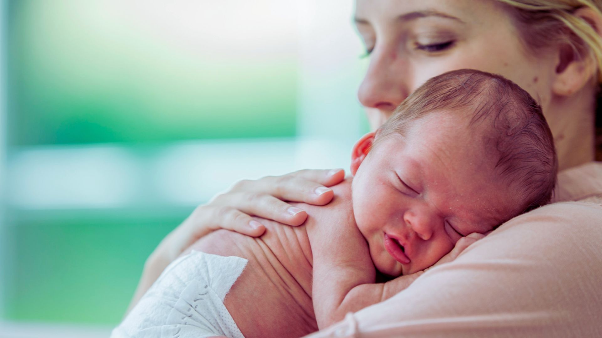A woman gently cradles a newborn baby in her arms, showcasing a tender moment of maternal care.