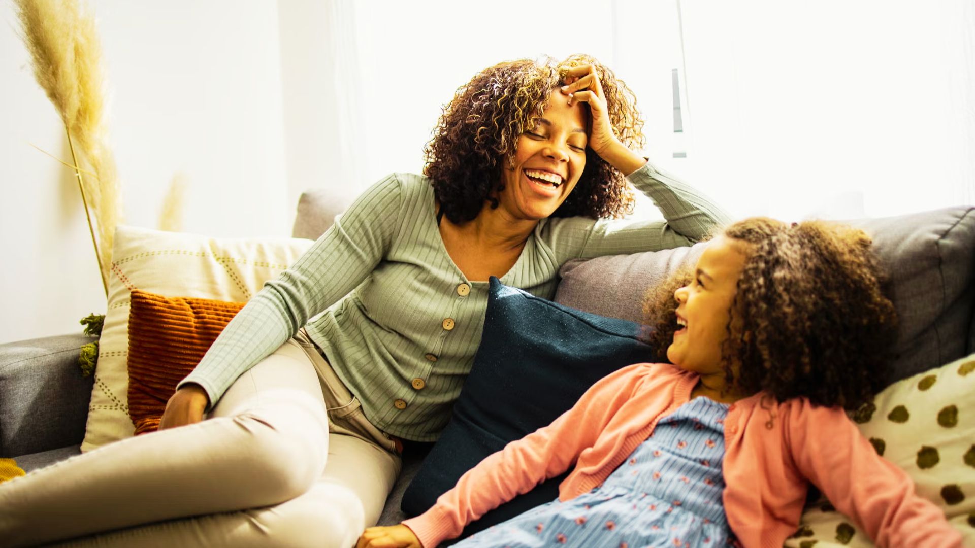 A woman and a young girl sit together on a couch, sharing a moment of comfort and companionship.