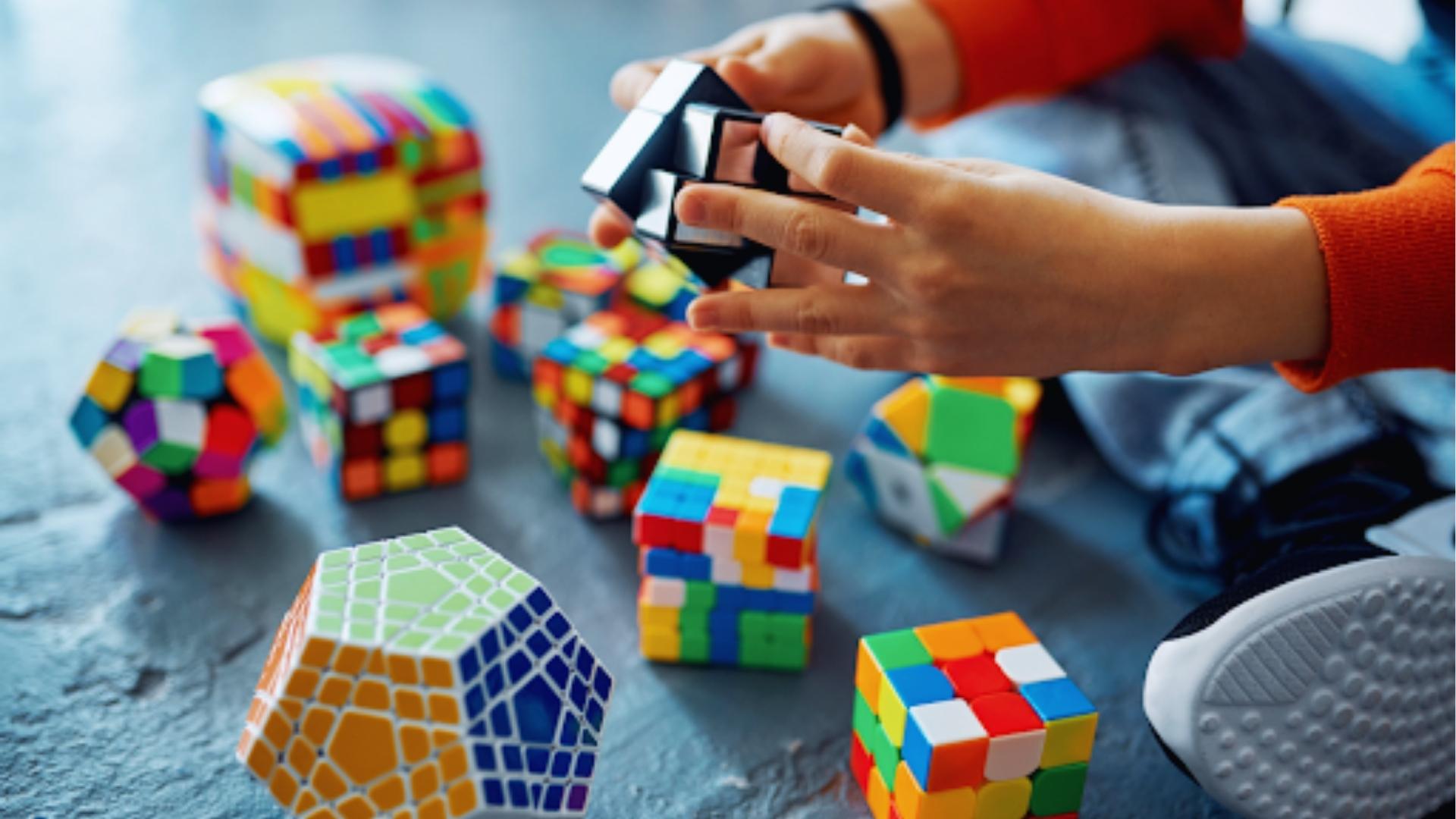 Child solves colorful Rubik’s cubes and puzzles on floor