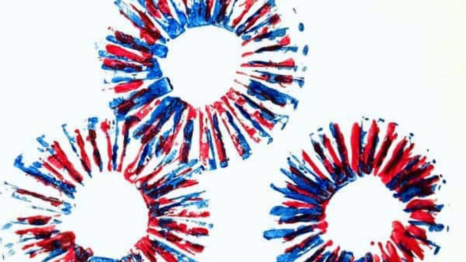 Three red and blue paint fireworks stamped on white paper using a circular printing tool.