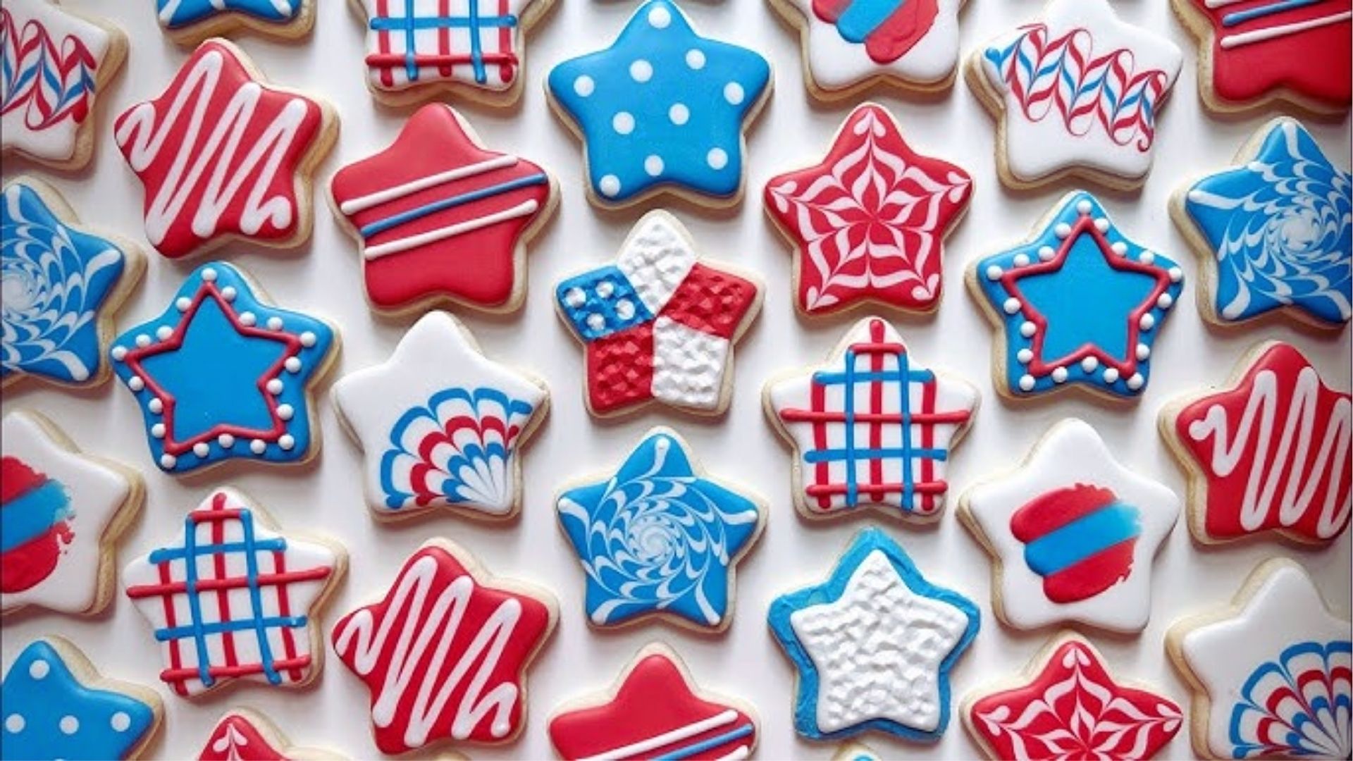 Star-shaped sugar cookies decorated with red, white, and blue icing in stripes, dots, and swirl patterns.