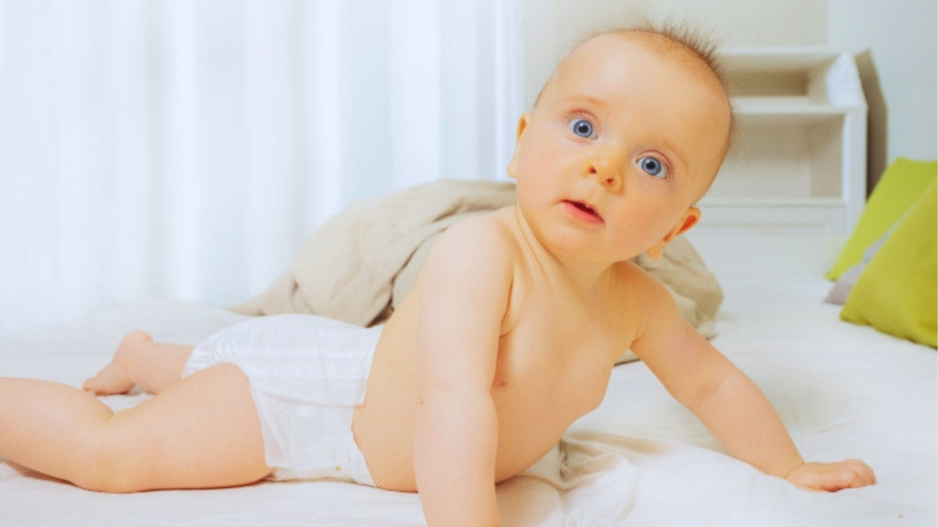 Alert baby doing tummy time on bed, a developmental milestone where head movements help build neck strength and coordination.